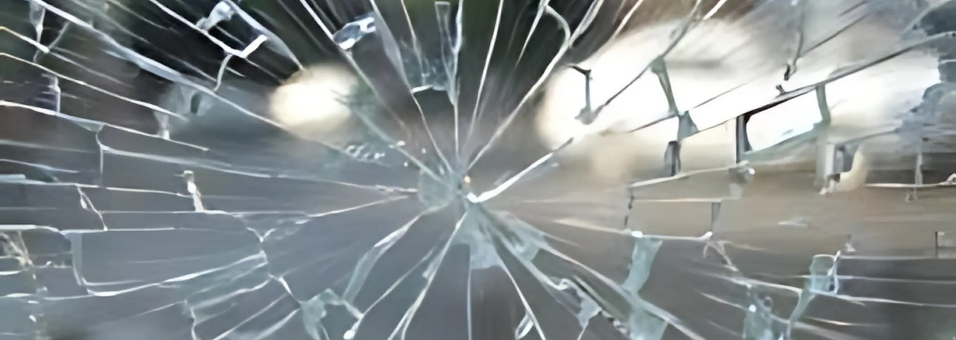 Shattered glass with cracks radiating outwards. Light is visible through the broken pane.
