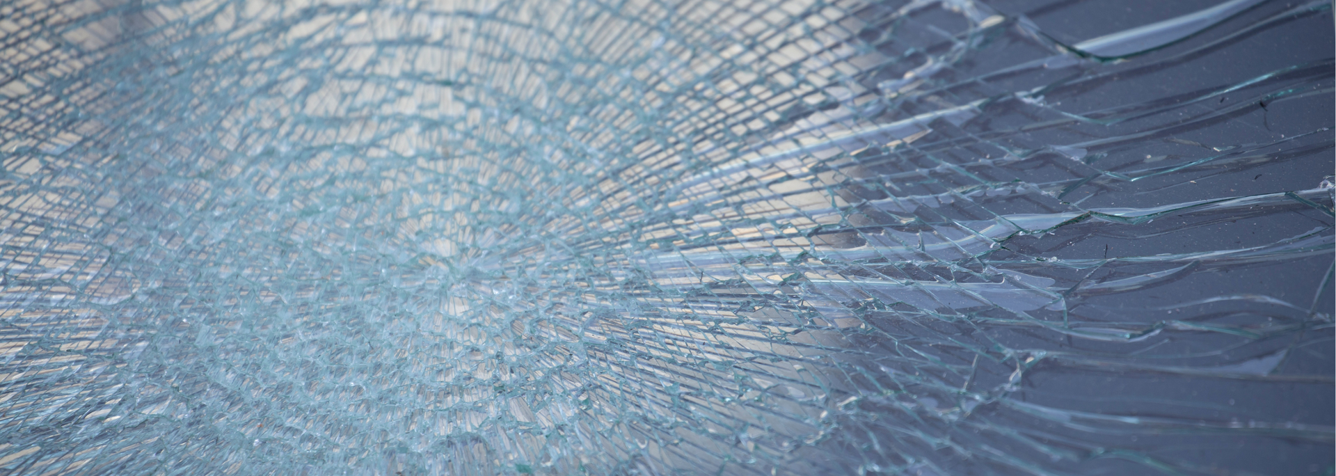 Cracked glass, with radiating fractures from a central impact point.