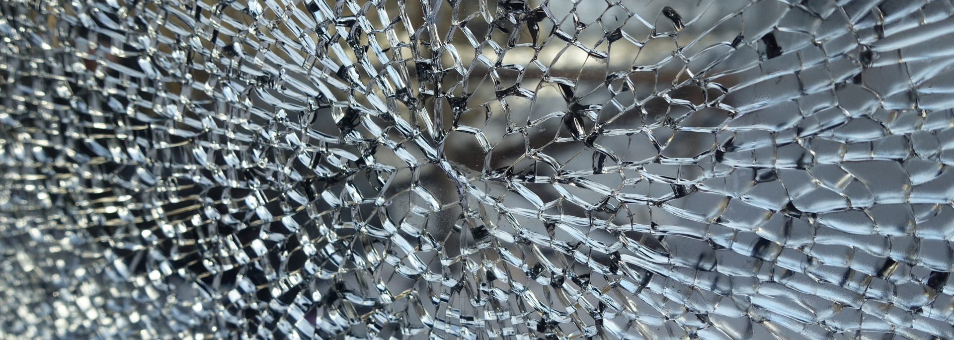 Shattered glass with a central impact point, showing a spiderweb pattern of cracks.