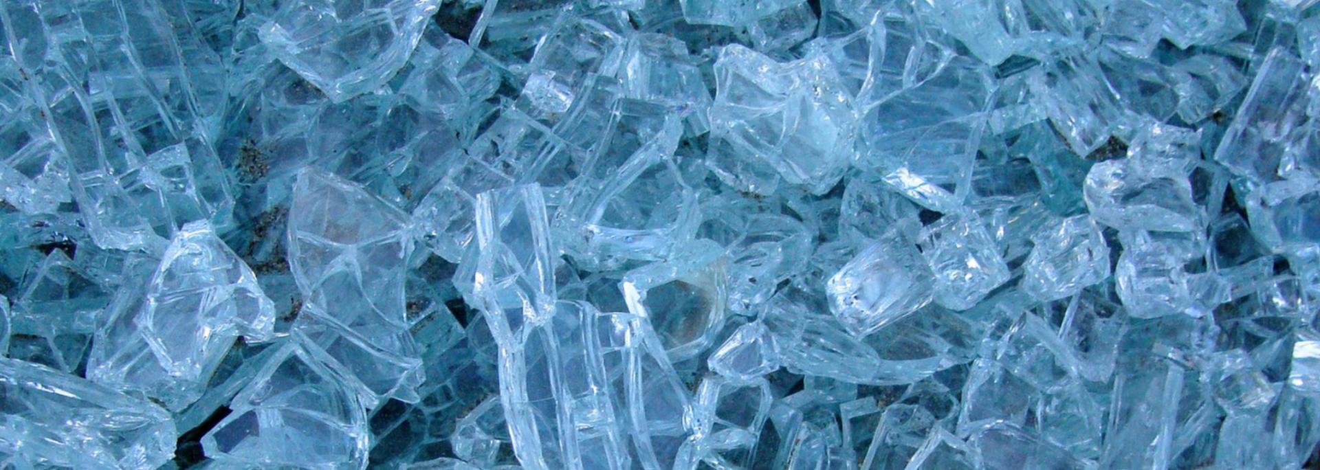 Close-up of broken glass, showing many sharp shards in shades of blue and white.