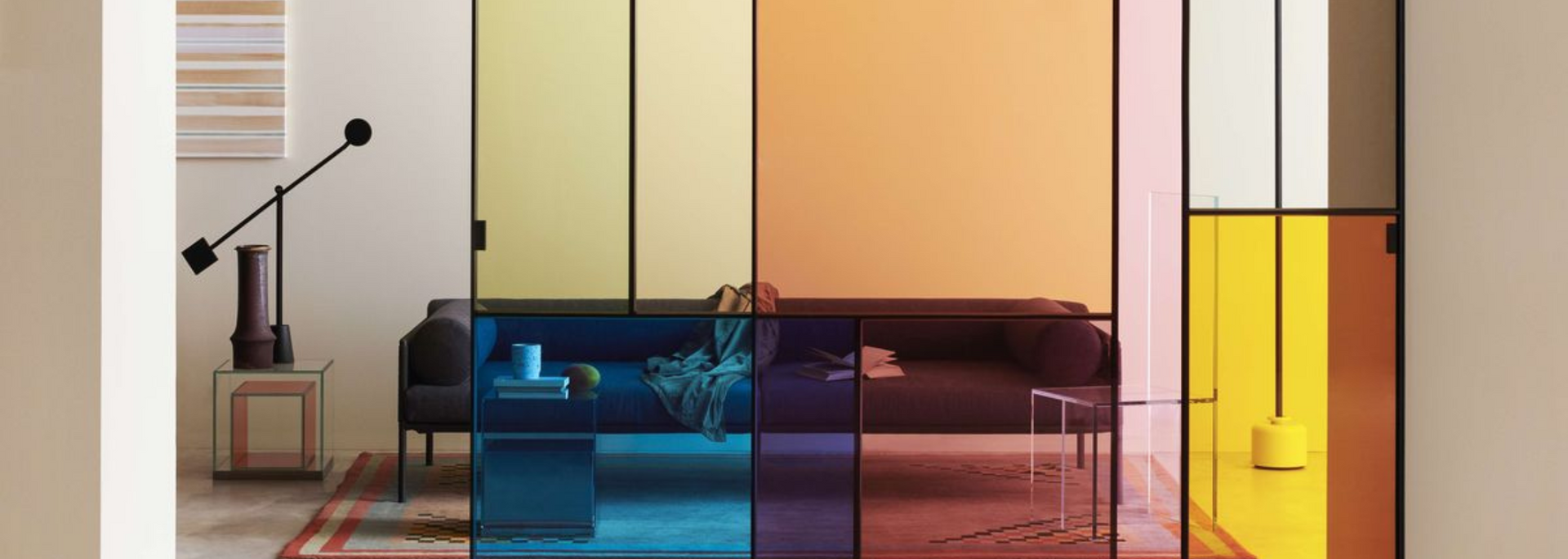 Room divider with colored glass panels, framing living room furniture and decor.