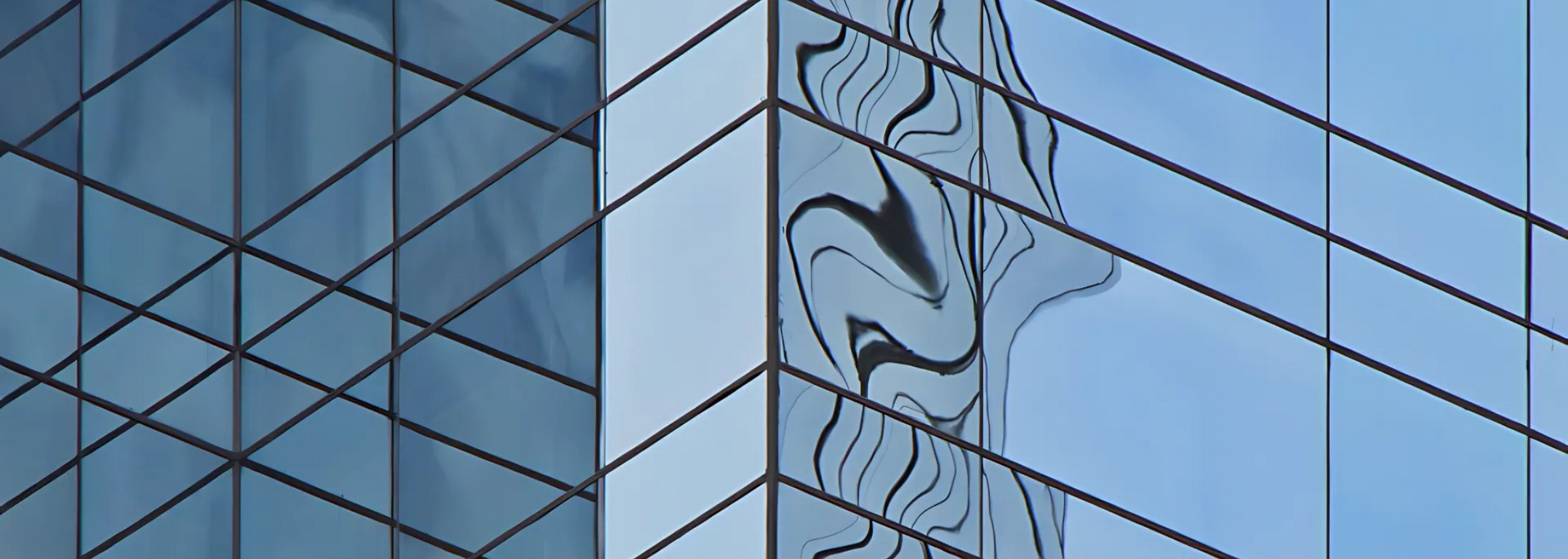 Close-up of a modern building with blue glass windows and reflective surfaces.