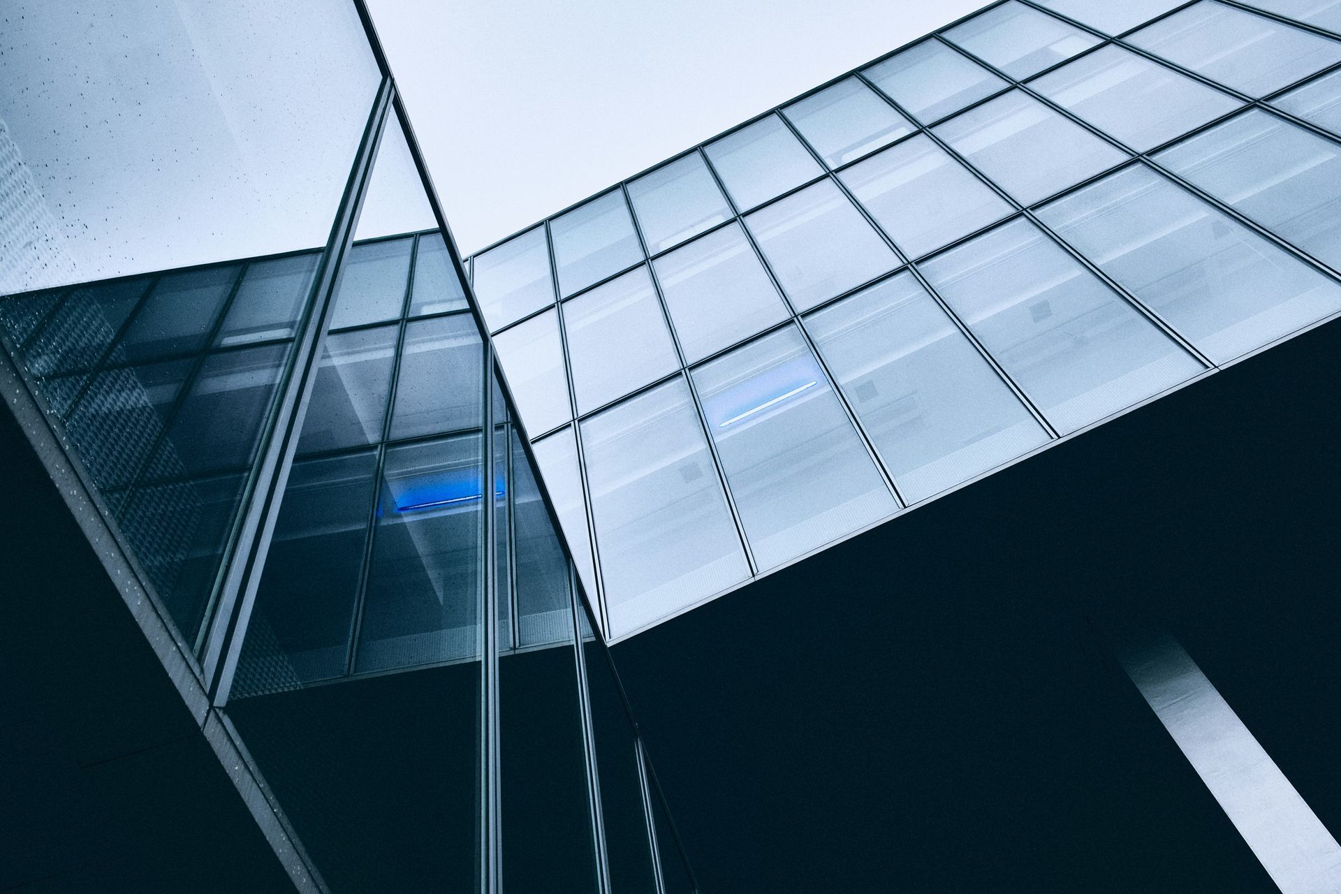 Modern glass building with reflections against a cloudy sky.