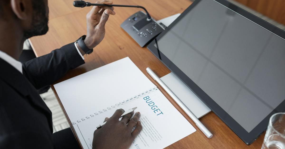 A person in a suit adjusts a microphone, reviewing a 