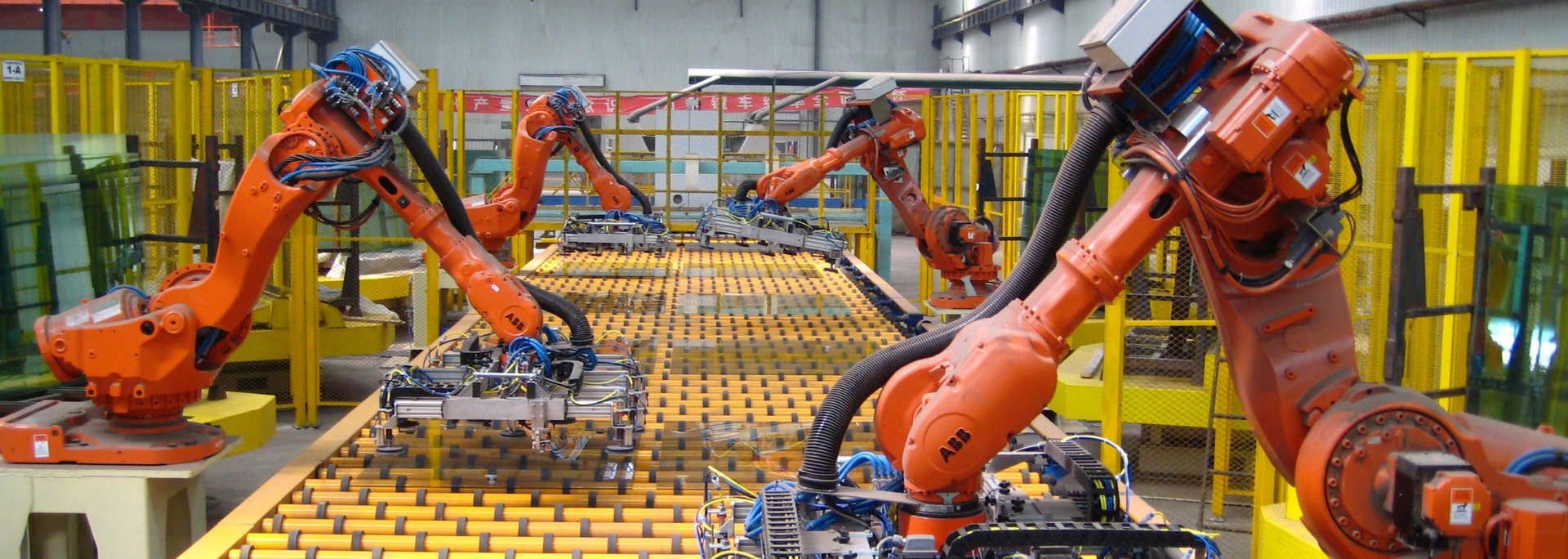 Industrial robots on an assembly line. Orange robot arms work on parts.