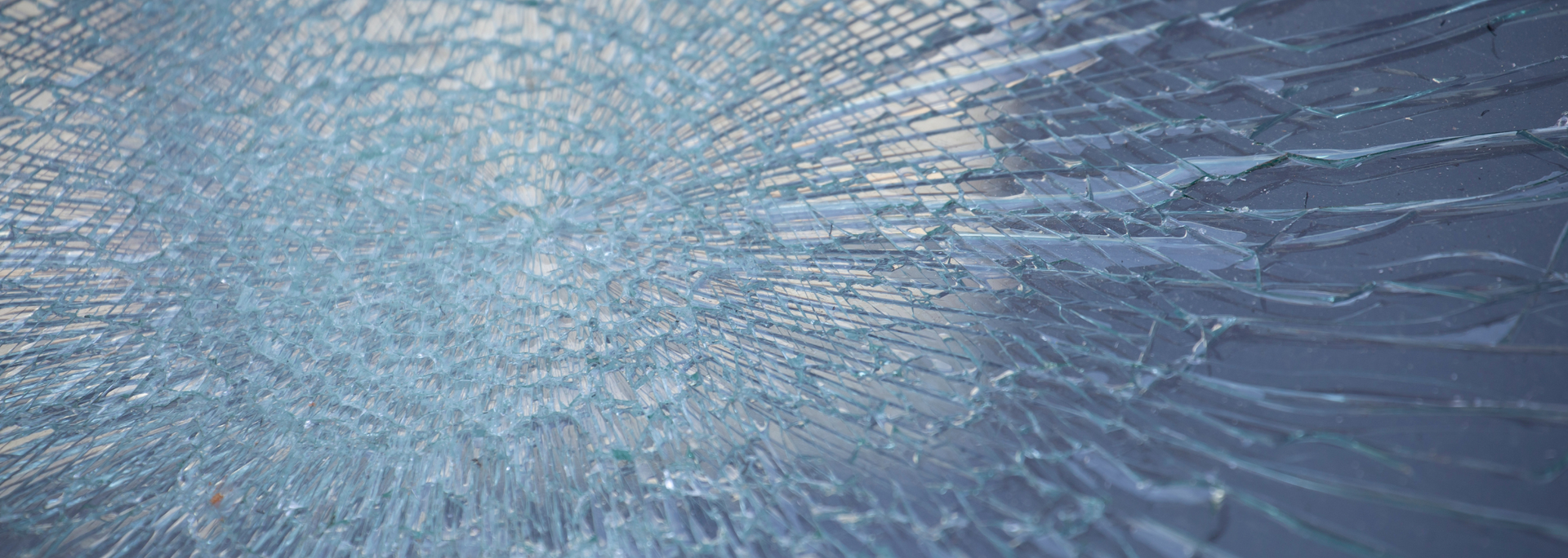 Shattered glass with cracks radiating outwards, light blue and white colors.