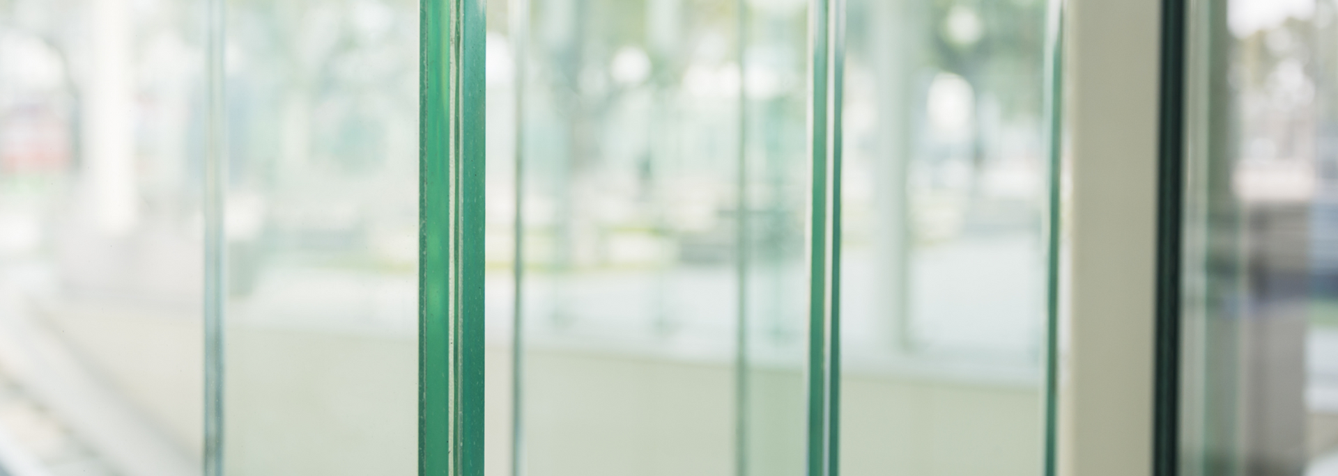 Glass panels of a modern building interior, with a blurred outdoor view visible through the panes.