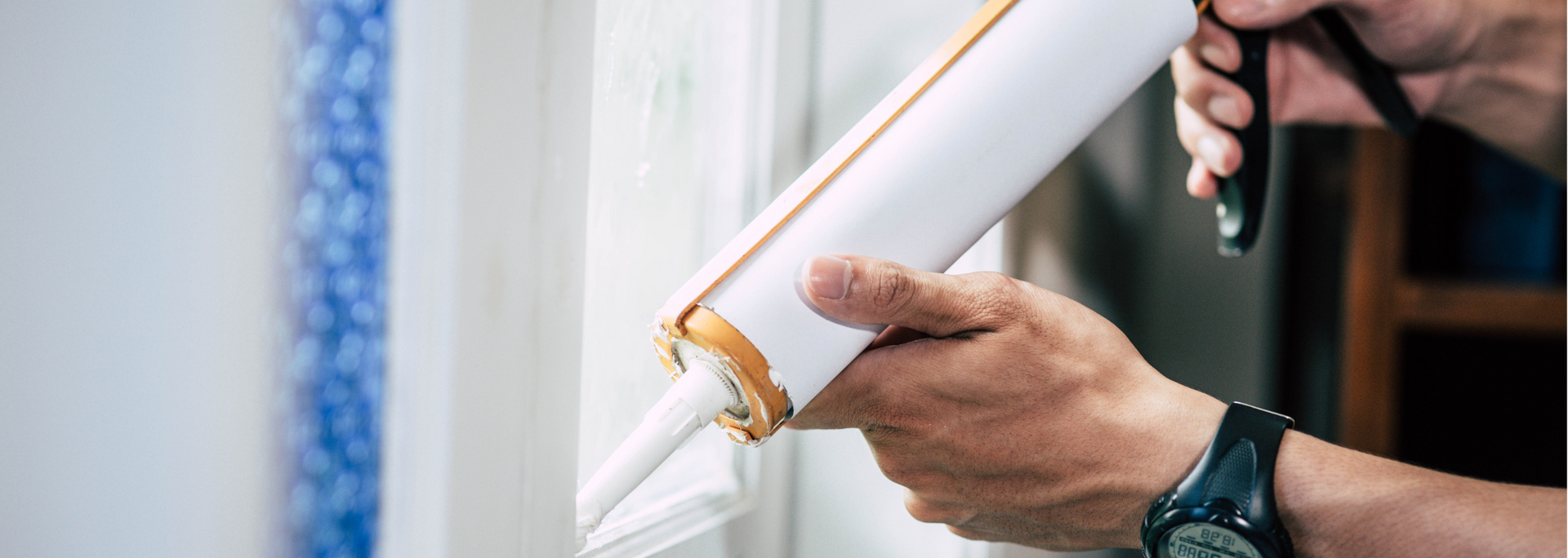 Person applying caulk from a tube with a caulk gun.