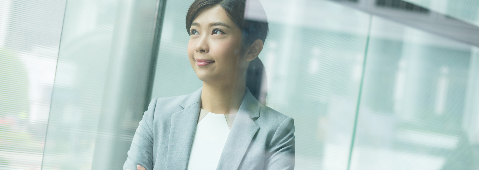 Woman in a gray suit looks out a window.