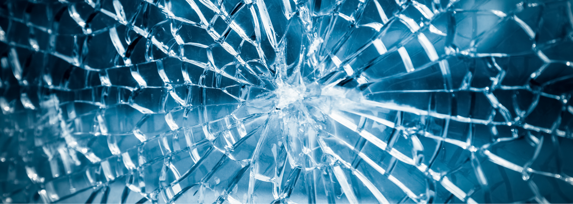 Shattered glass with a web of cracks, radiating from a central point, blue tones.