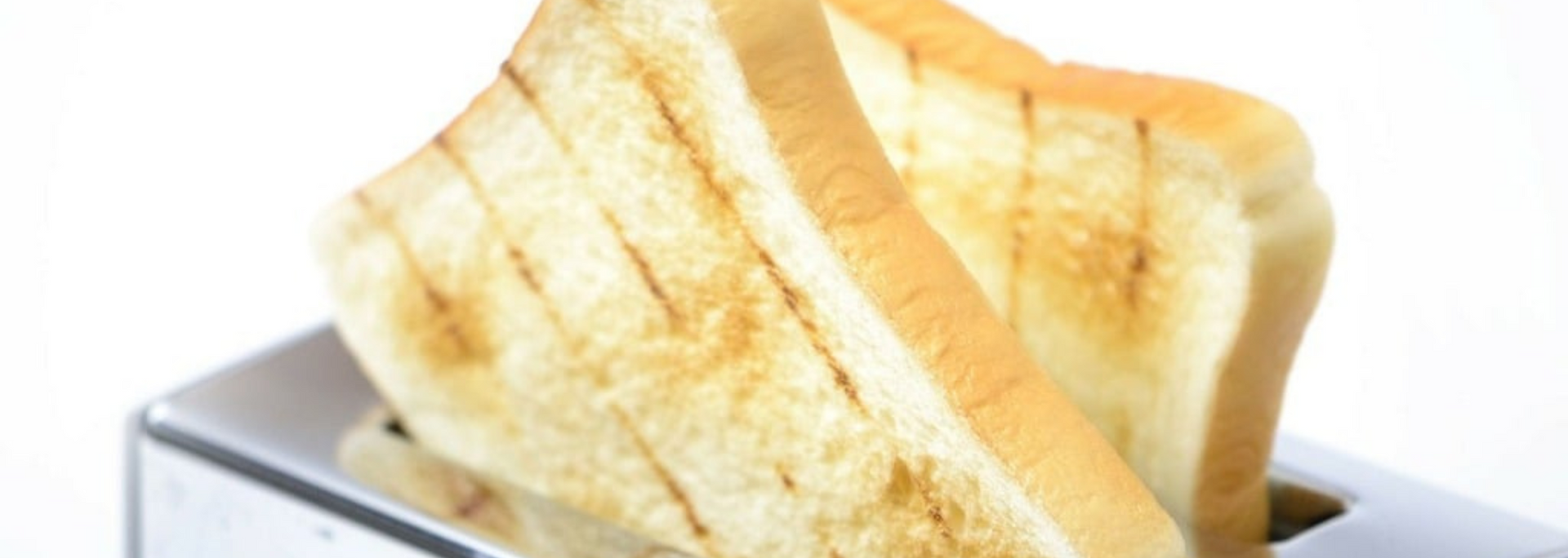 Toasted bread slices in a chrome toaster against a white background.