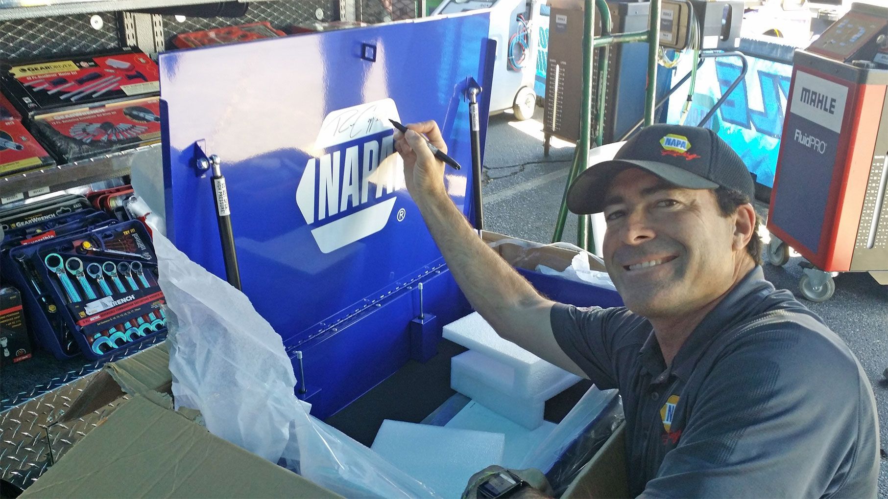 A man is smiling in front of a napa sign | Zia Automotive