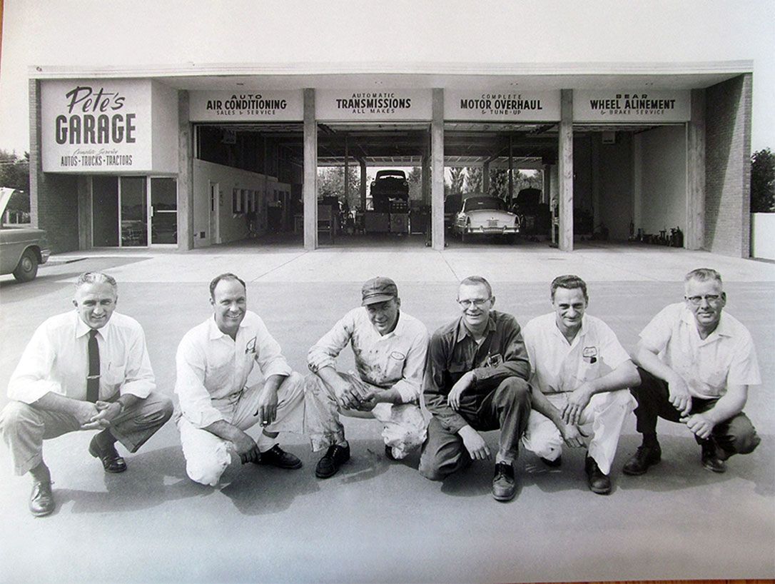 A group of men are squatting in front of a garage | ZIa Automotive