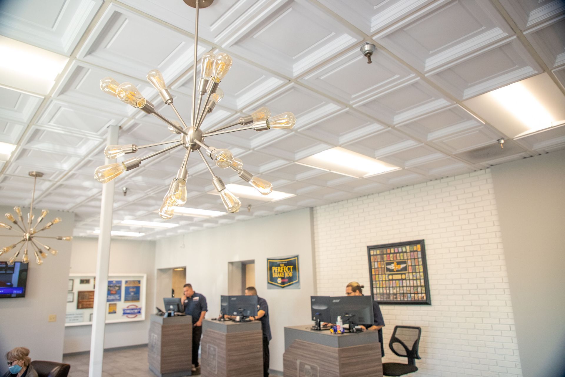 A group of people are standing at a counter in a room with a chandelier hanging from the ceiling. | Zia Automotive