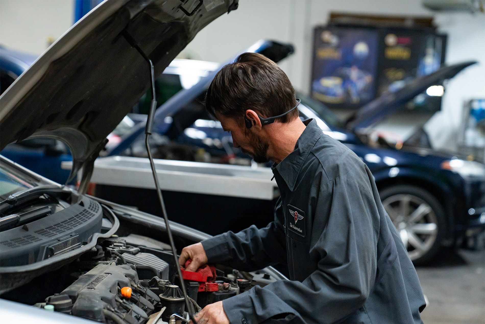 A man is working on the engine of a car in a garage. | Zia Automotive