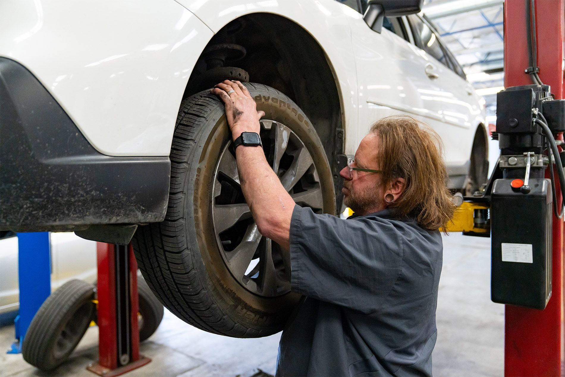 A man is changing a tire on a car on a lift. | Zia Automotive