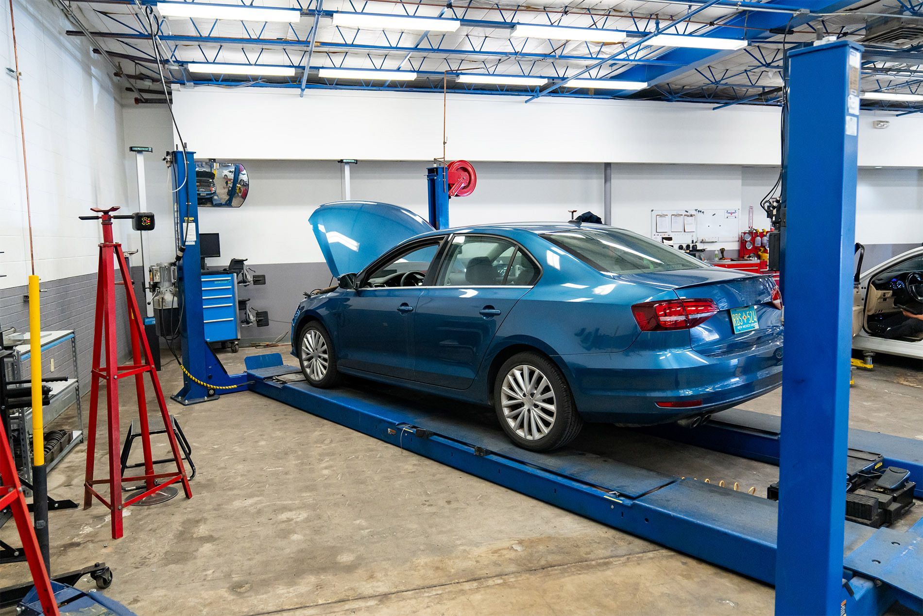A blue car is sitting on a lift in a garage. | Zia Automotive