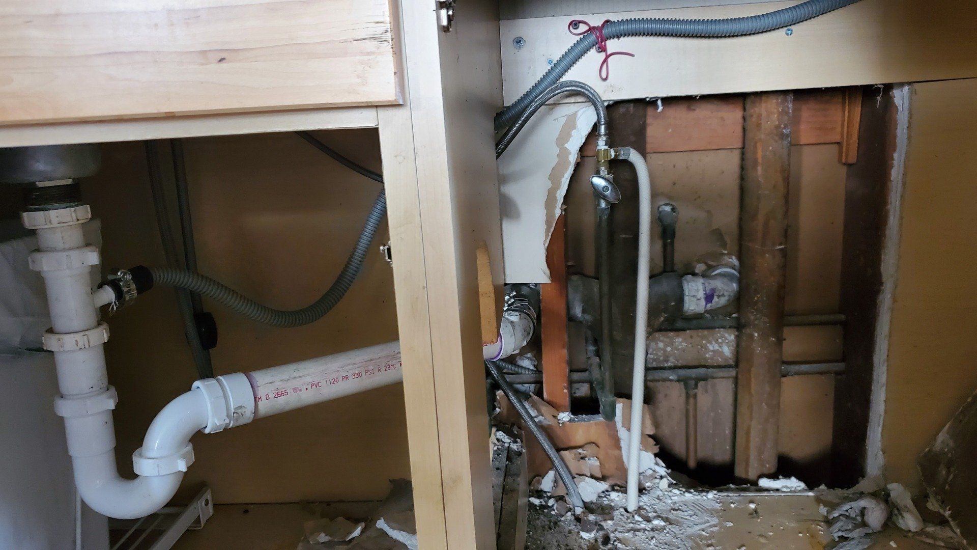 A kitchen sink with a lot of pipes underneath it