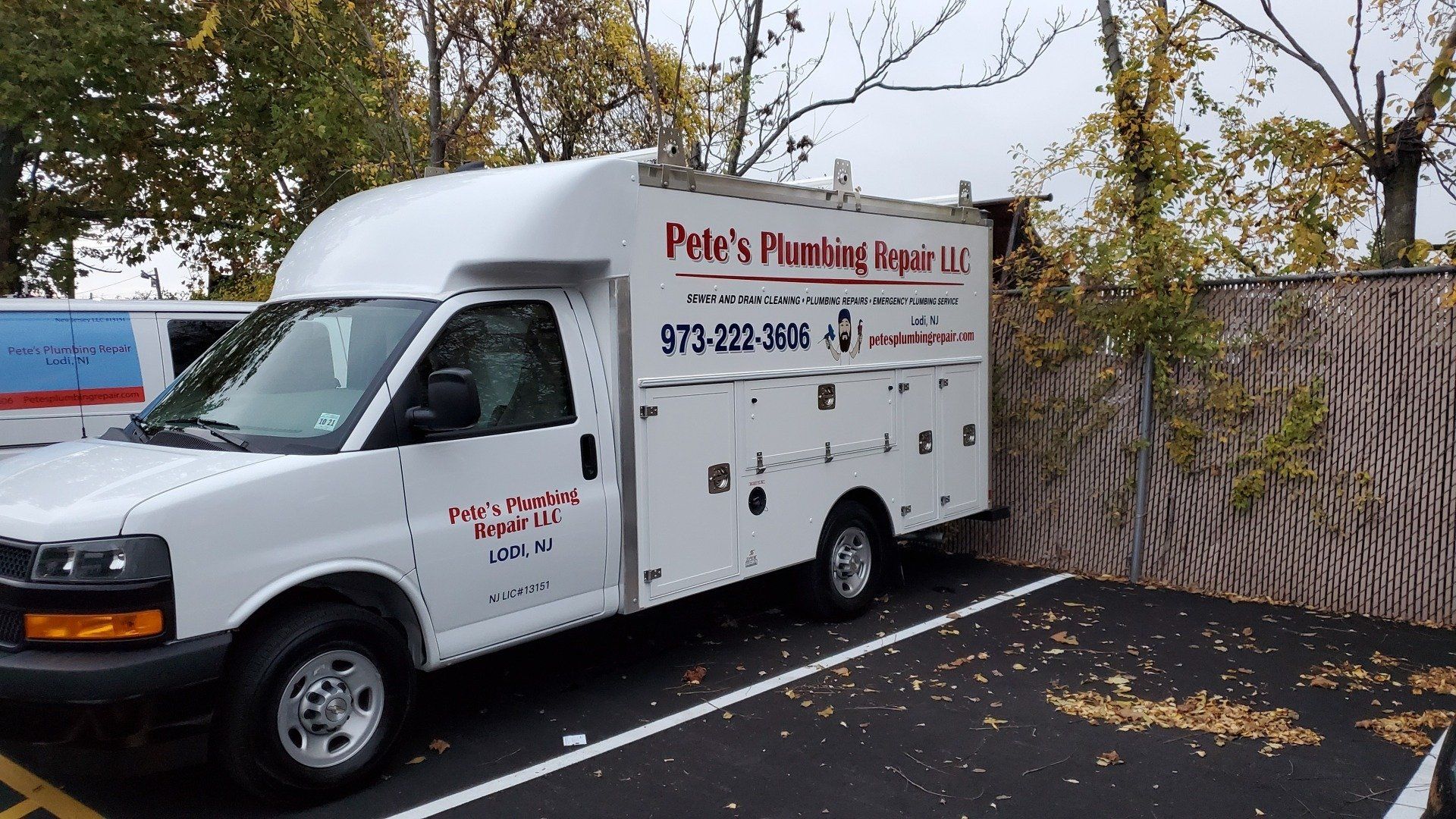 A white plumbing truck is parked in a parking lot