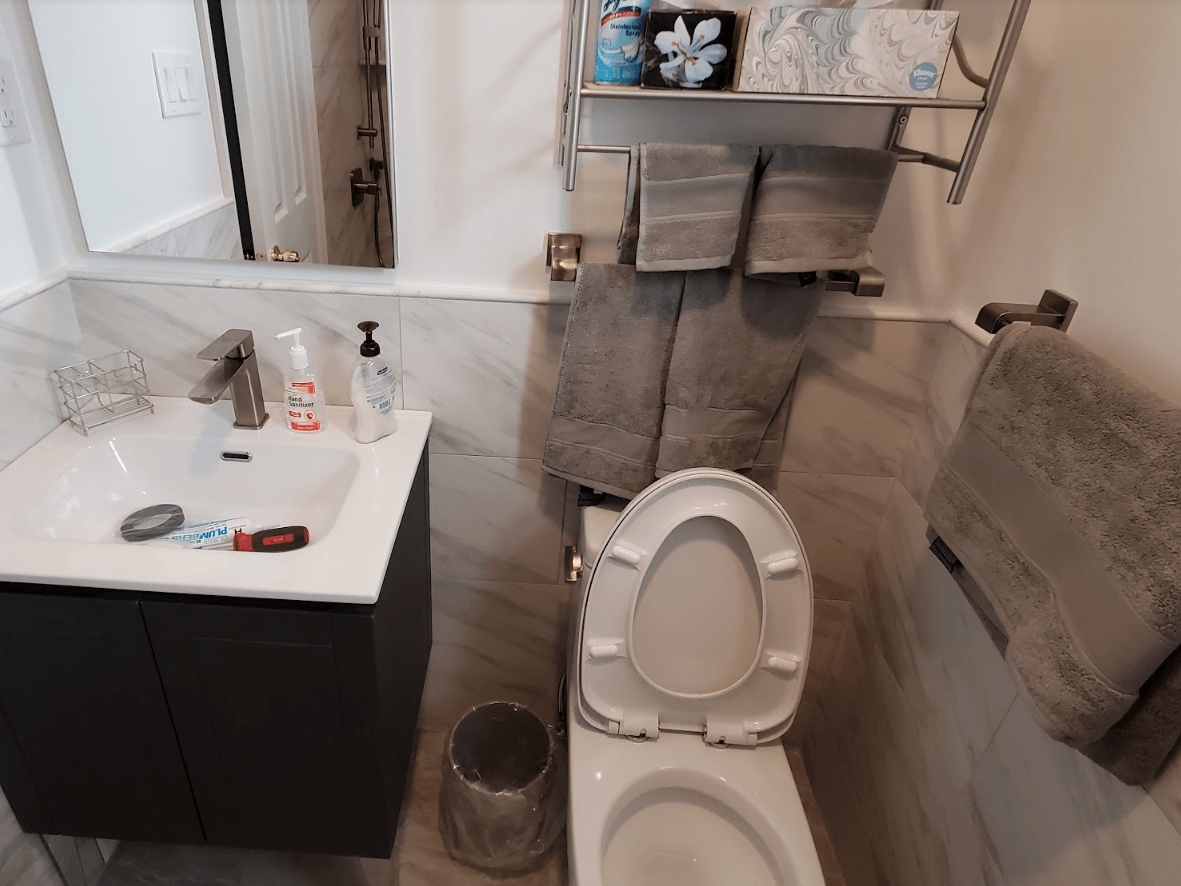 A bathroom with a toilet , sink and mirror.
