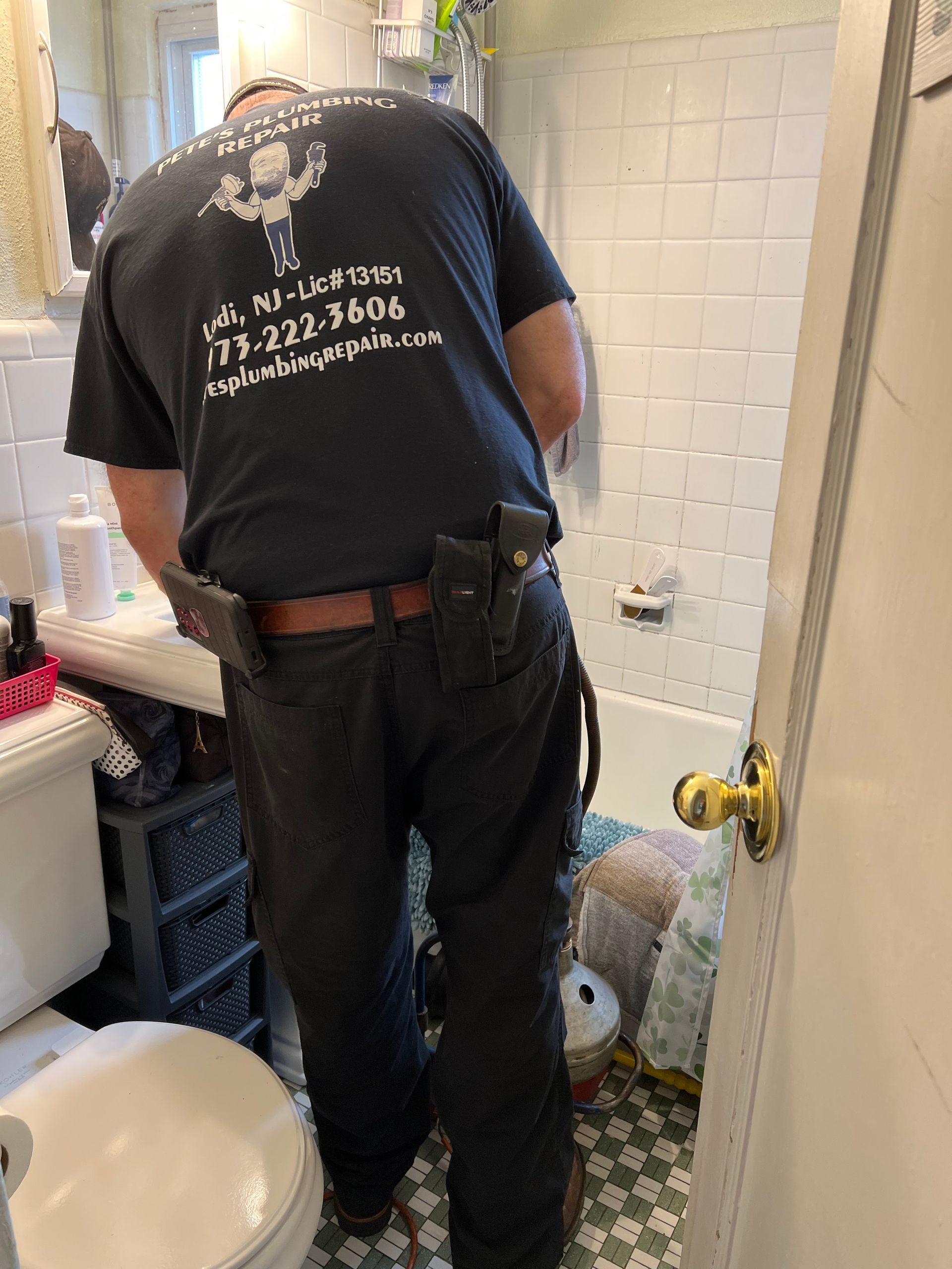 A man in a black shirt is working in a bathroom.