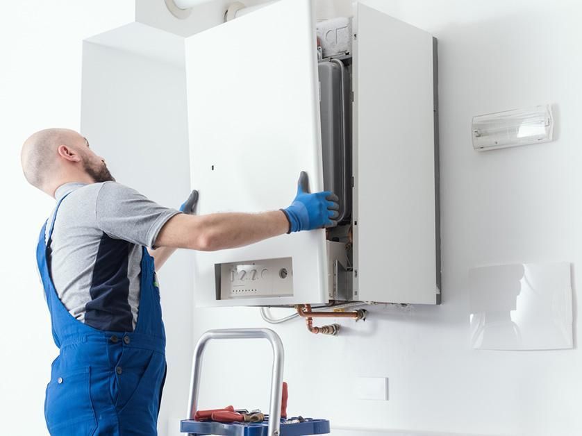 A man is installing a boiler on a wall.