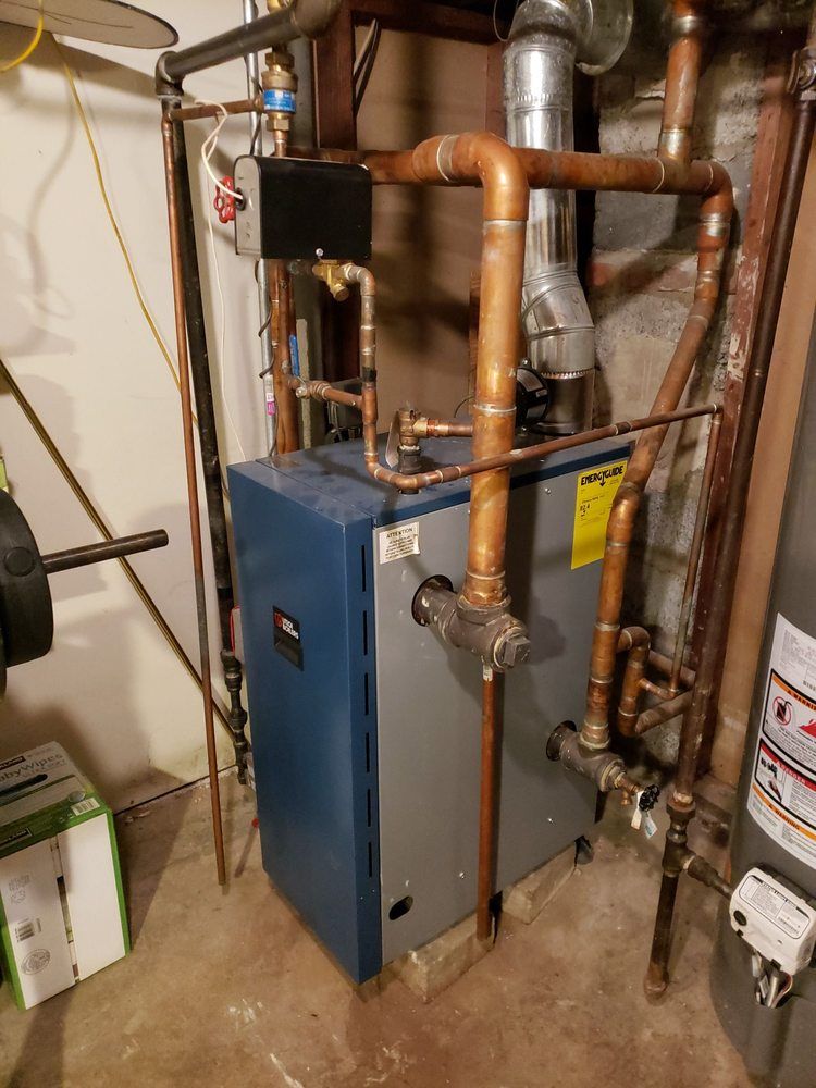 A blue boiler is sitting in a basement next to a water heater.