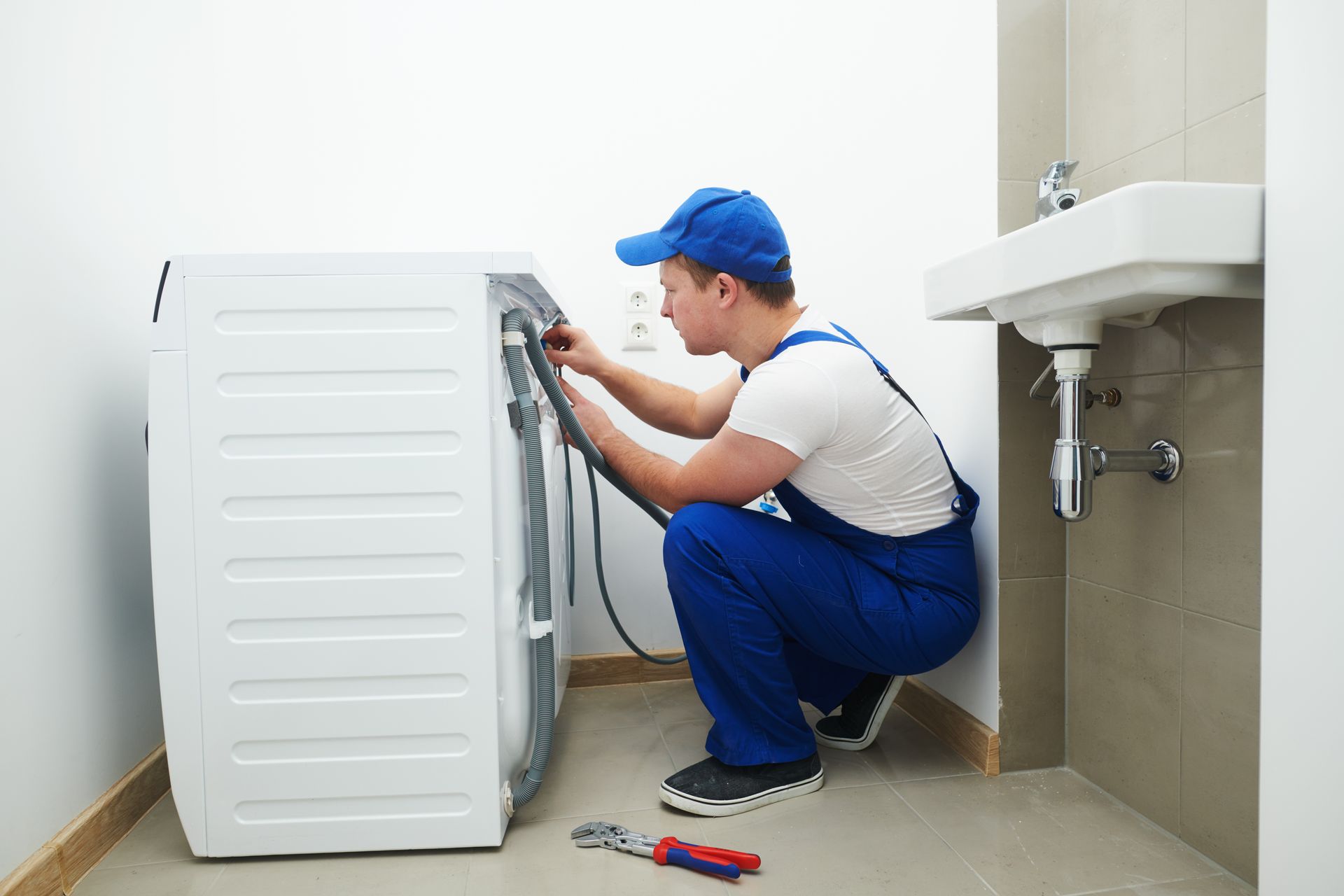 A man is fixing a washing machine in a bathroom.