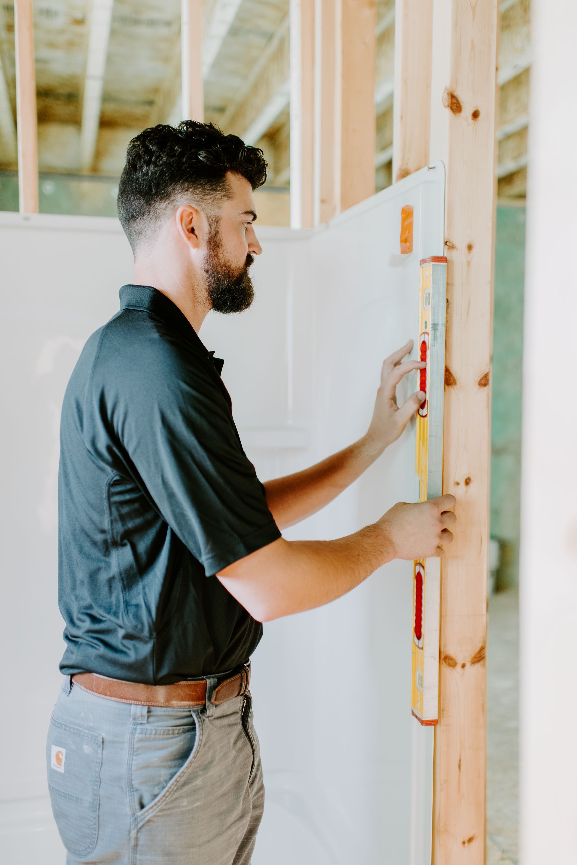 A man is measuring a wall with a level.