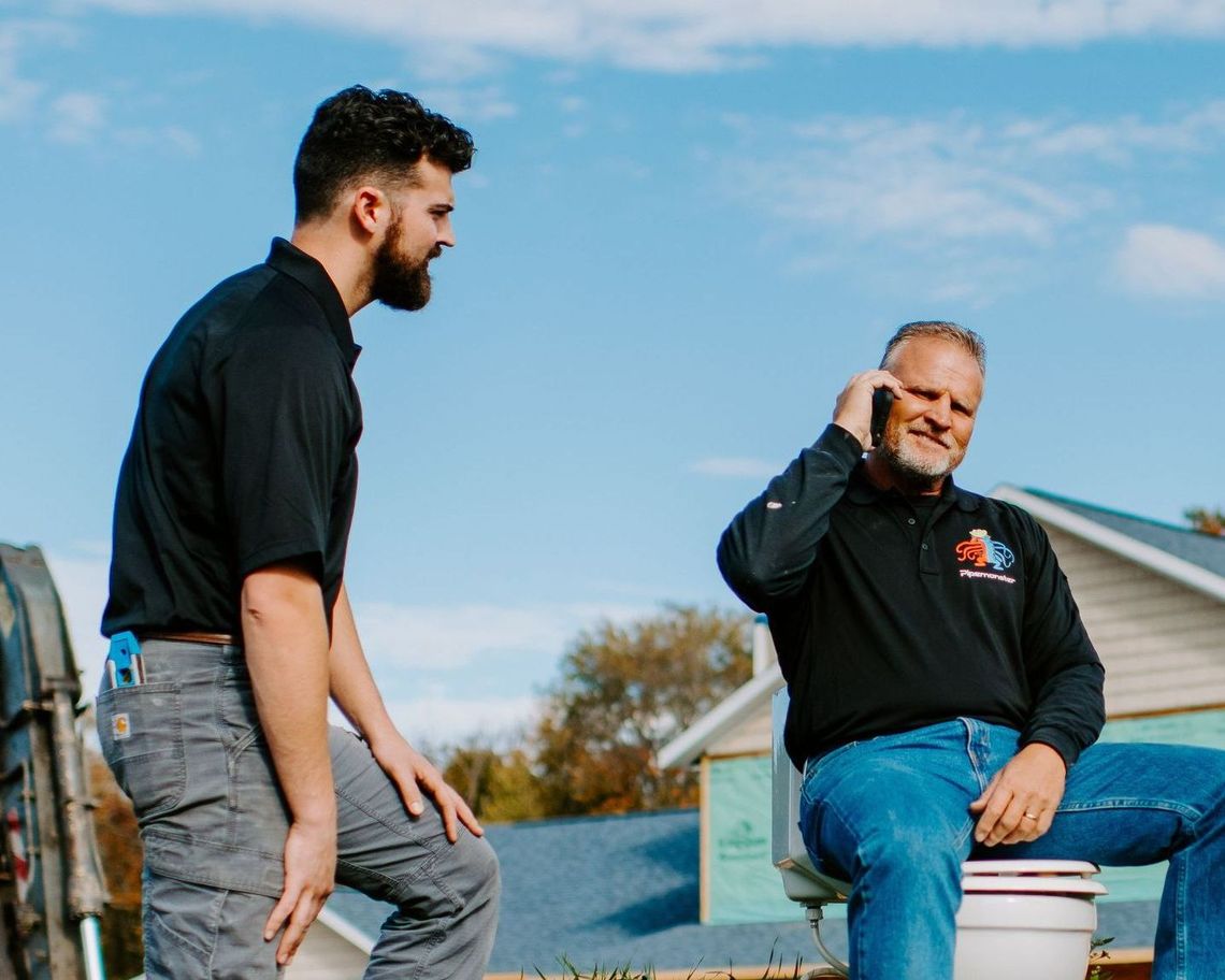 Two men are standing next to each other in a warehouse with their arms crossed.