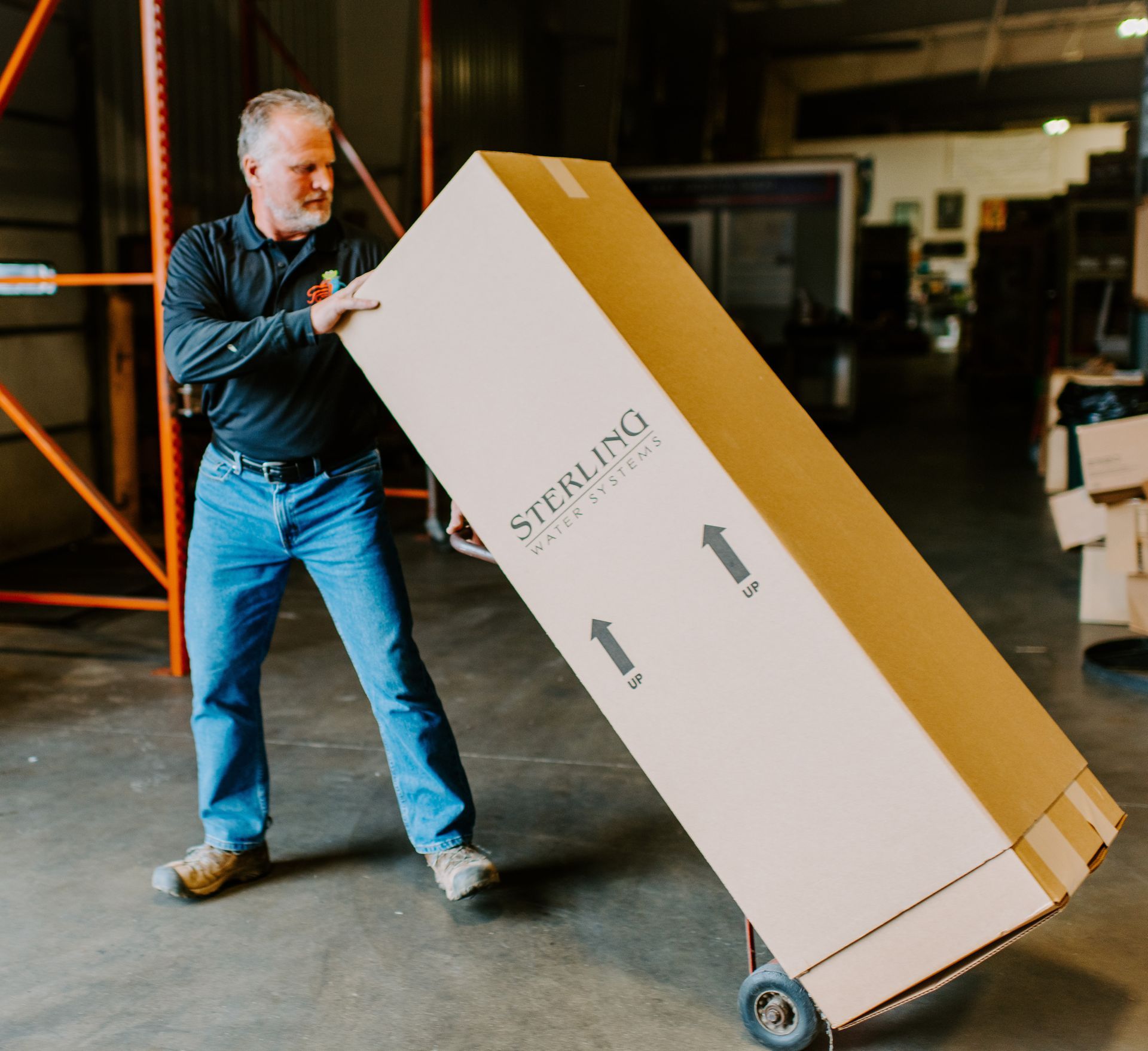 A man is pushing a sterling box on a cart
