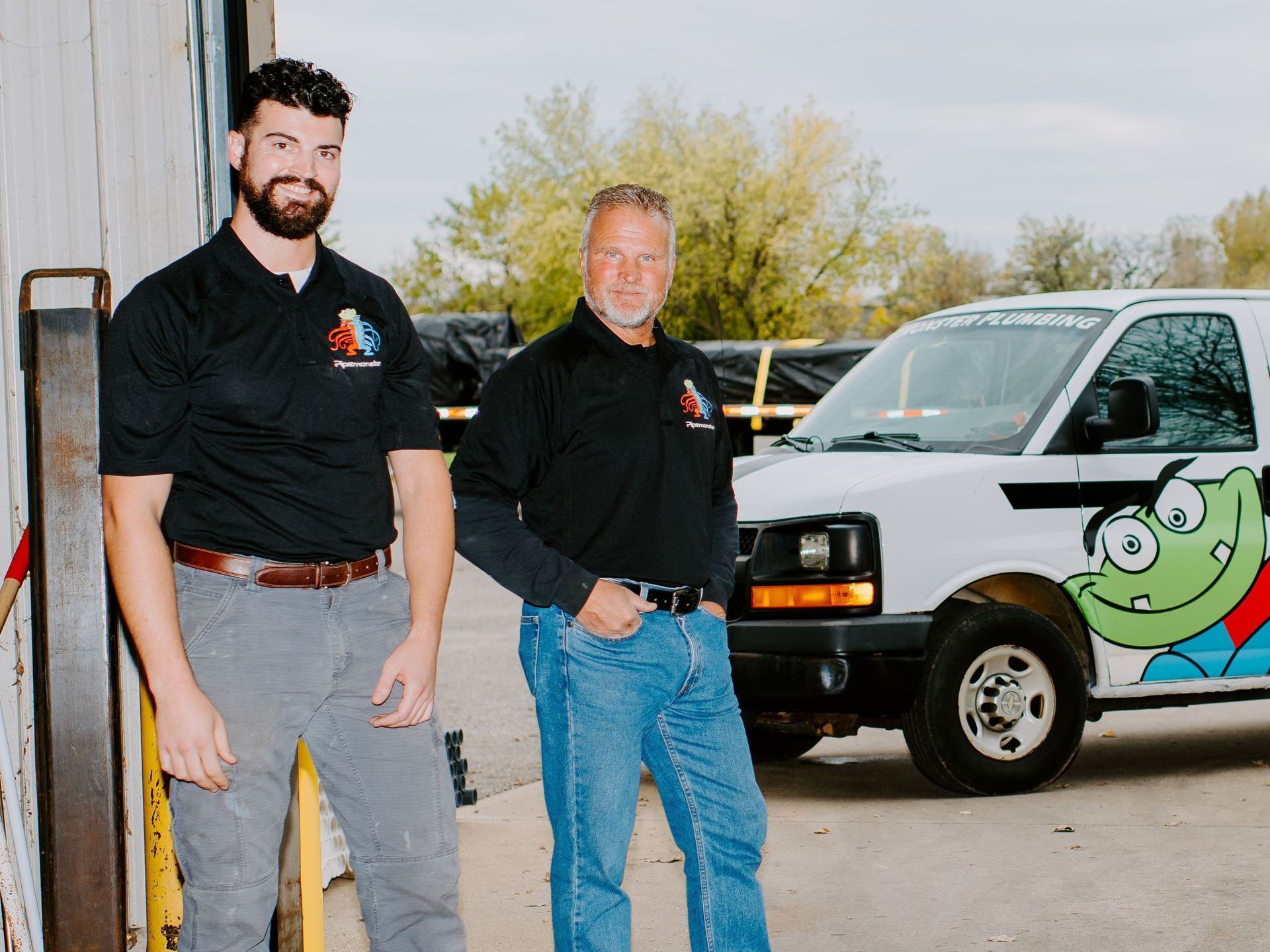 Two men are standing in front of a van with a frog on the side.