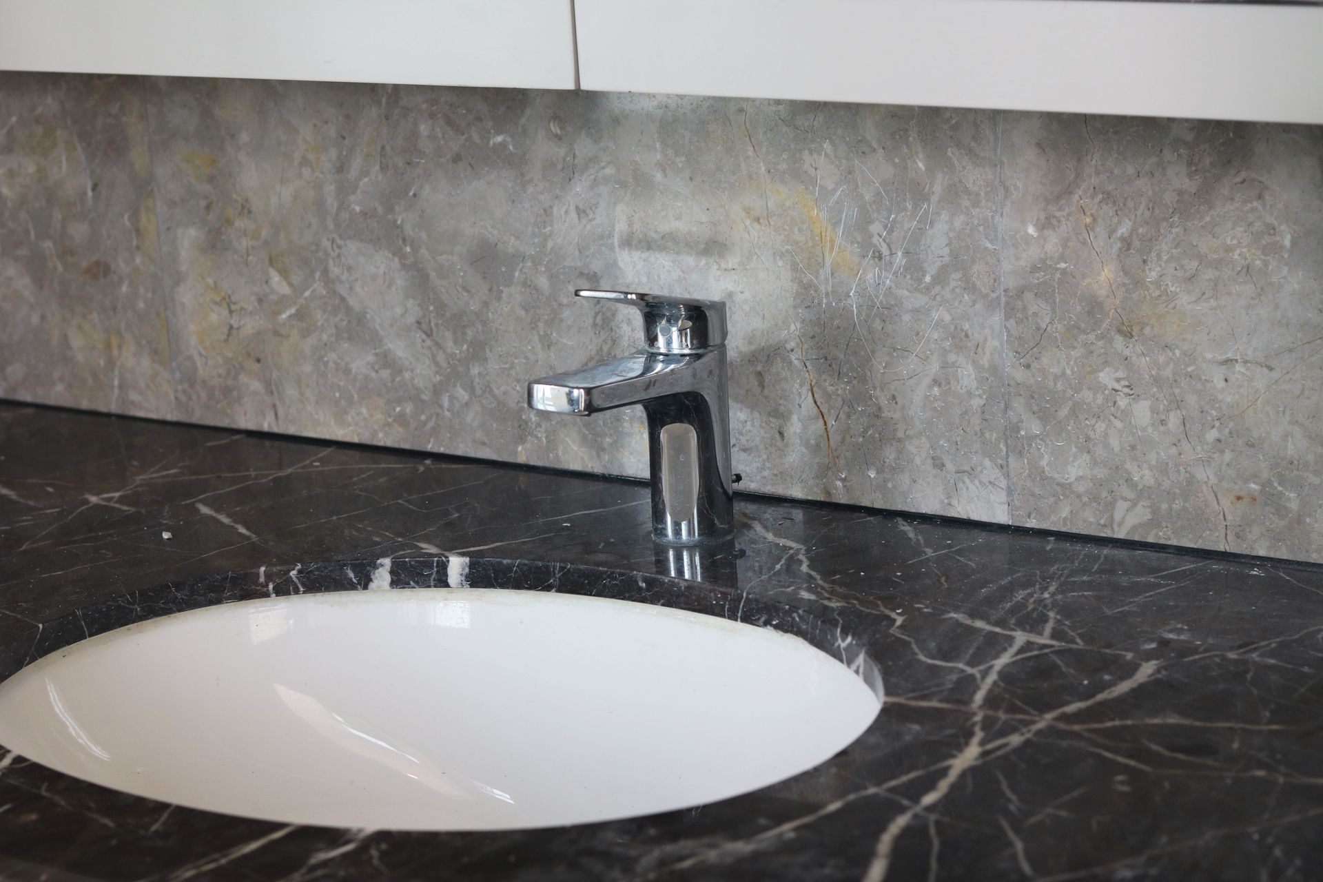 A bathroom sink with a faucet on a marble counter top.