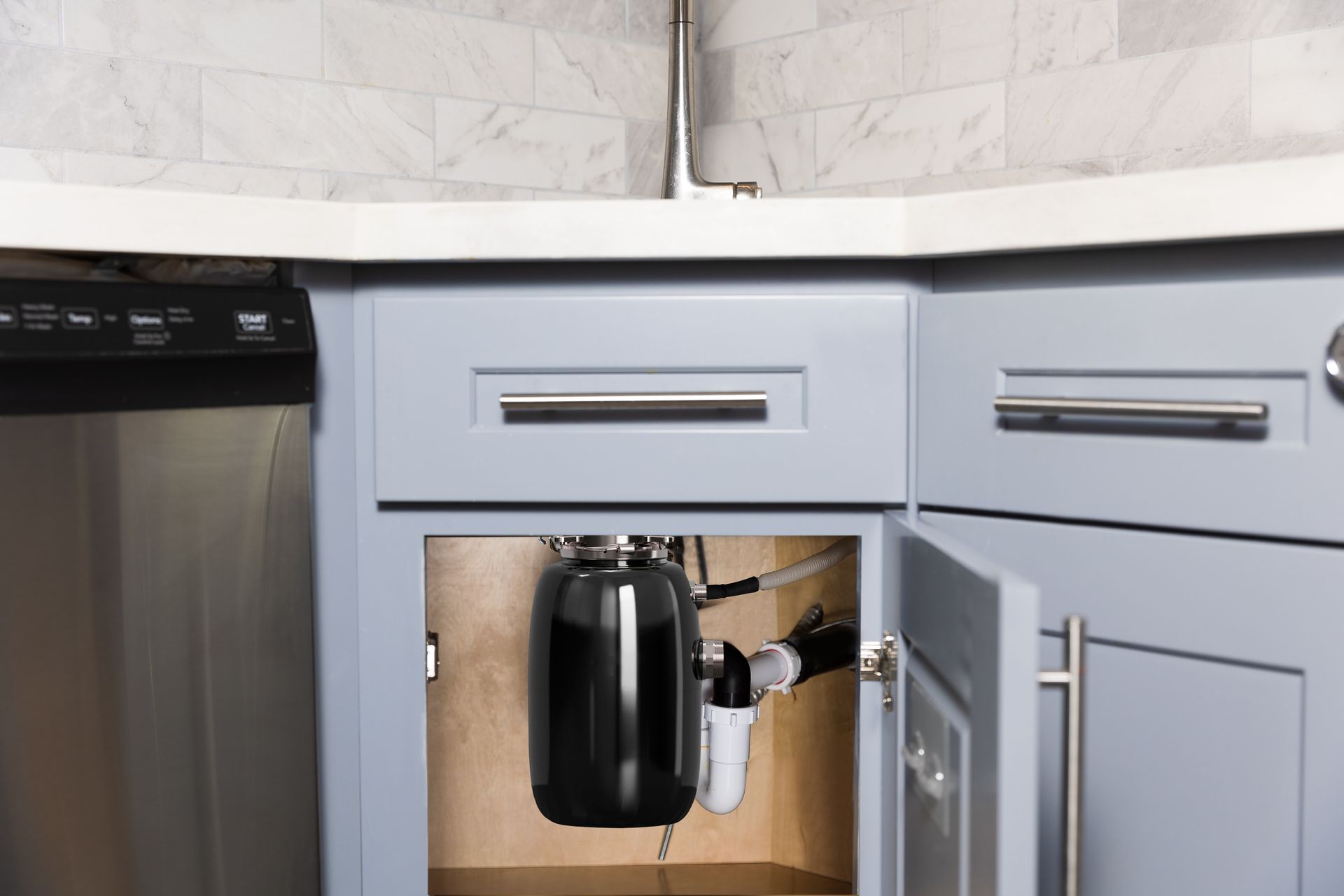 A kitchen sink with a trash can underneath it.