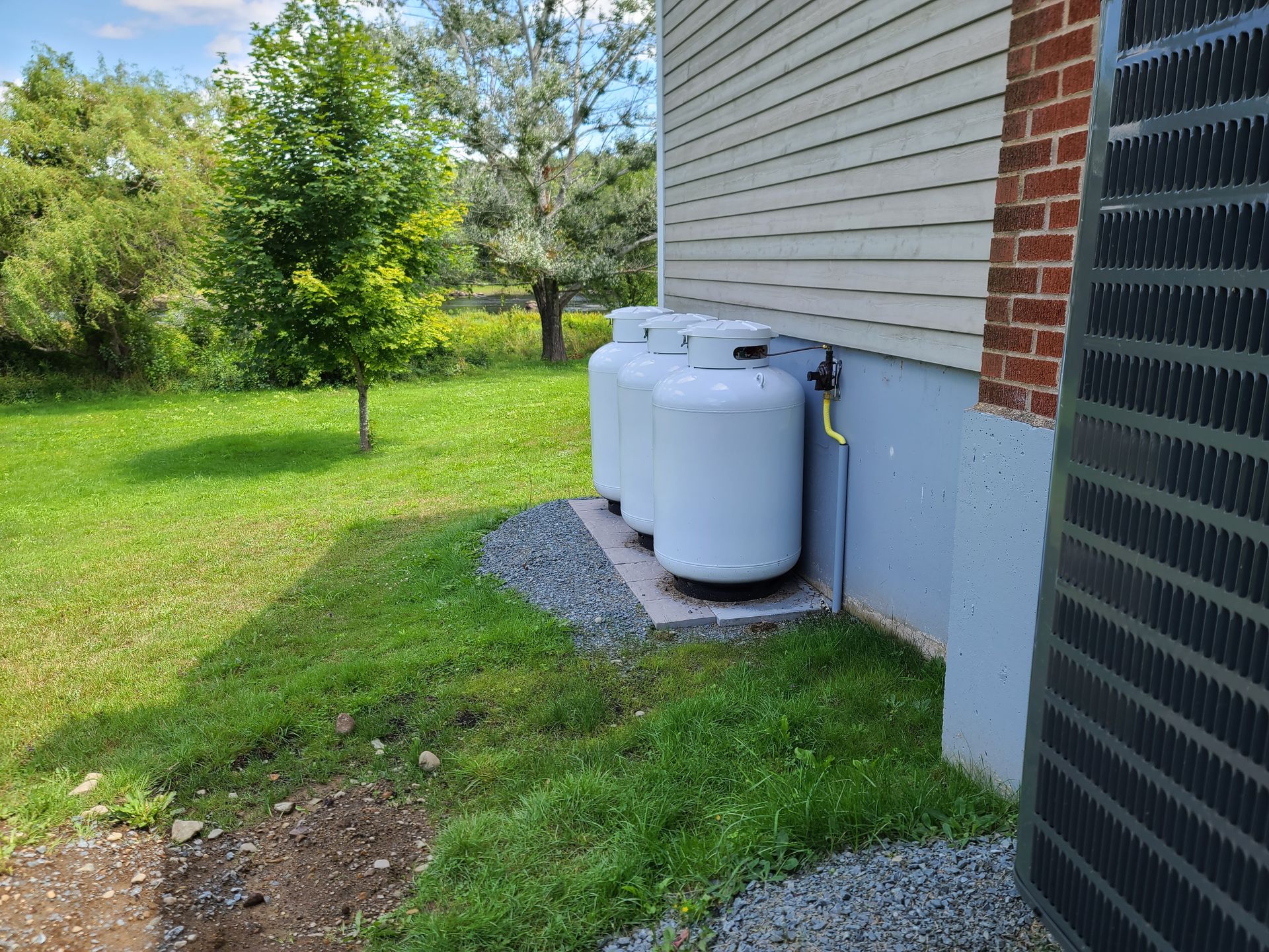 Three propane tanks are sitting on the side of a house.