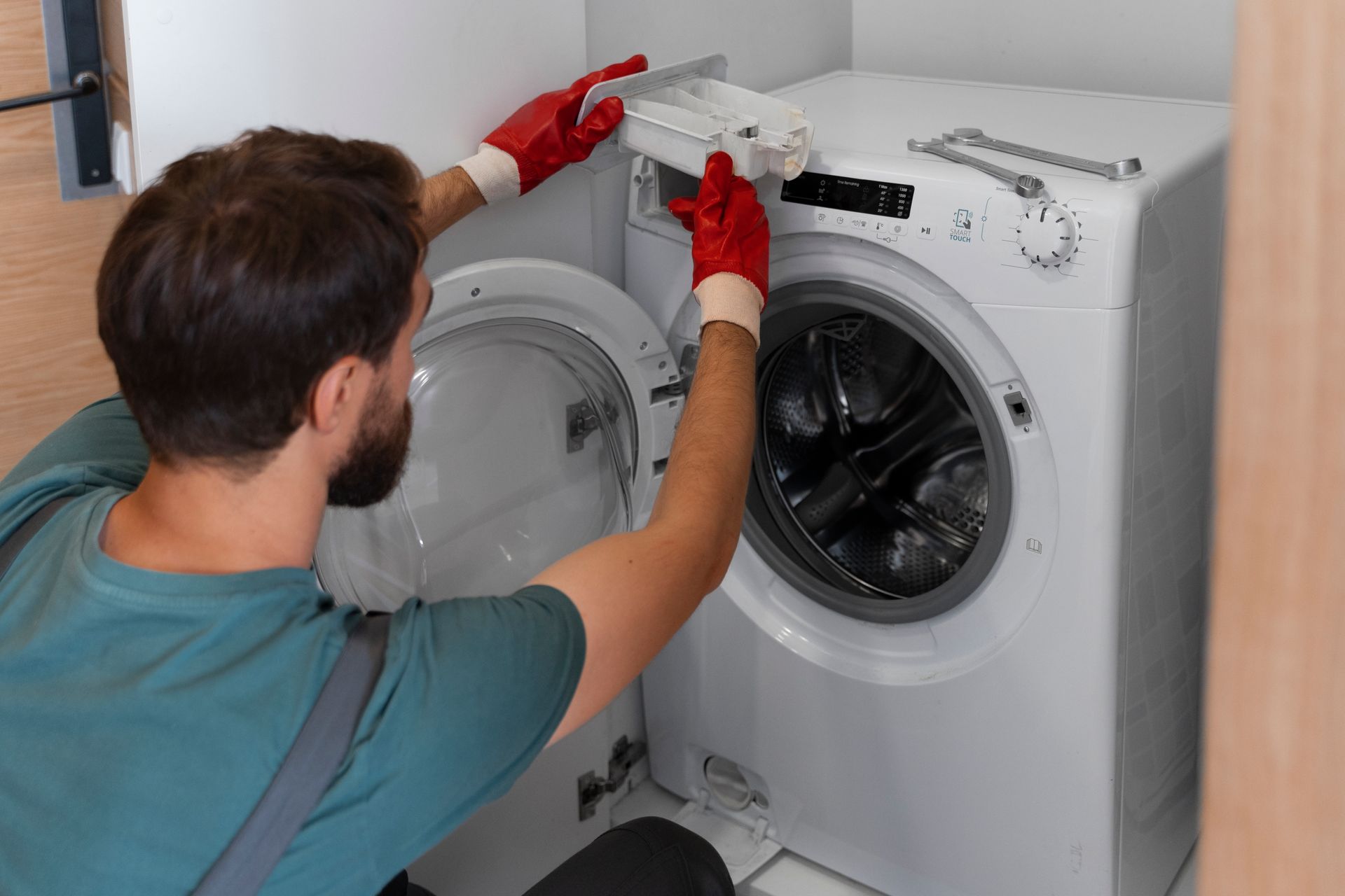 A man is fixing a washing machine in a bathroom.