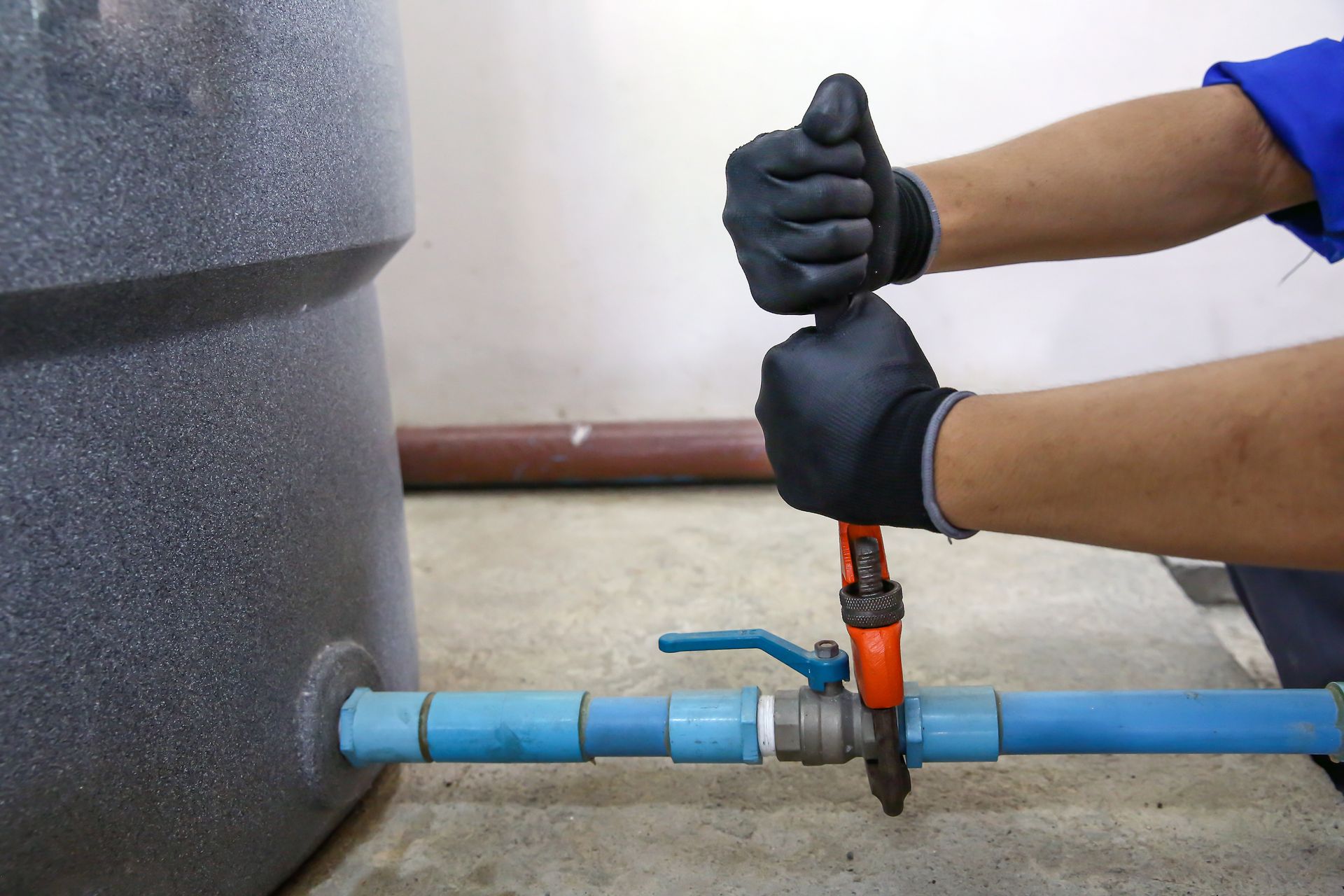 A person is fixing a water pipe with a wrench.