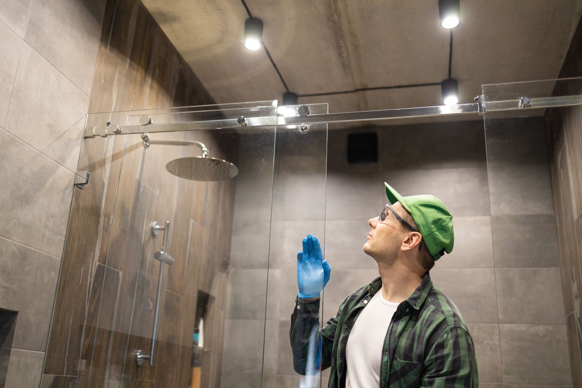 A man is cleaning a shower door in a bathroom.