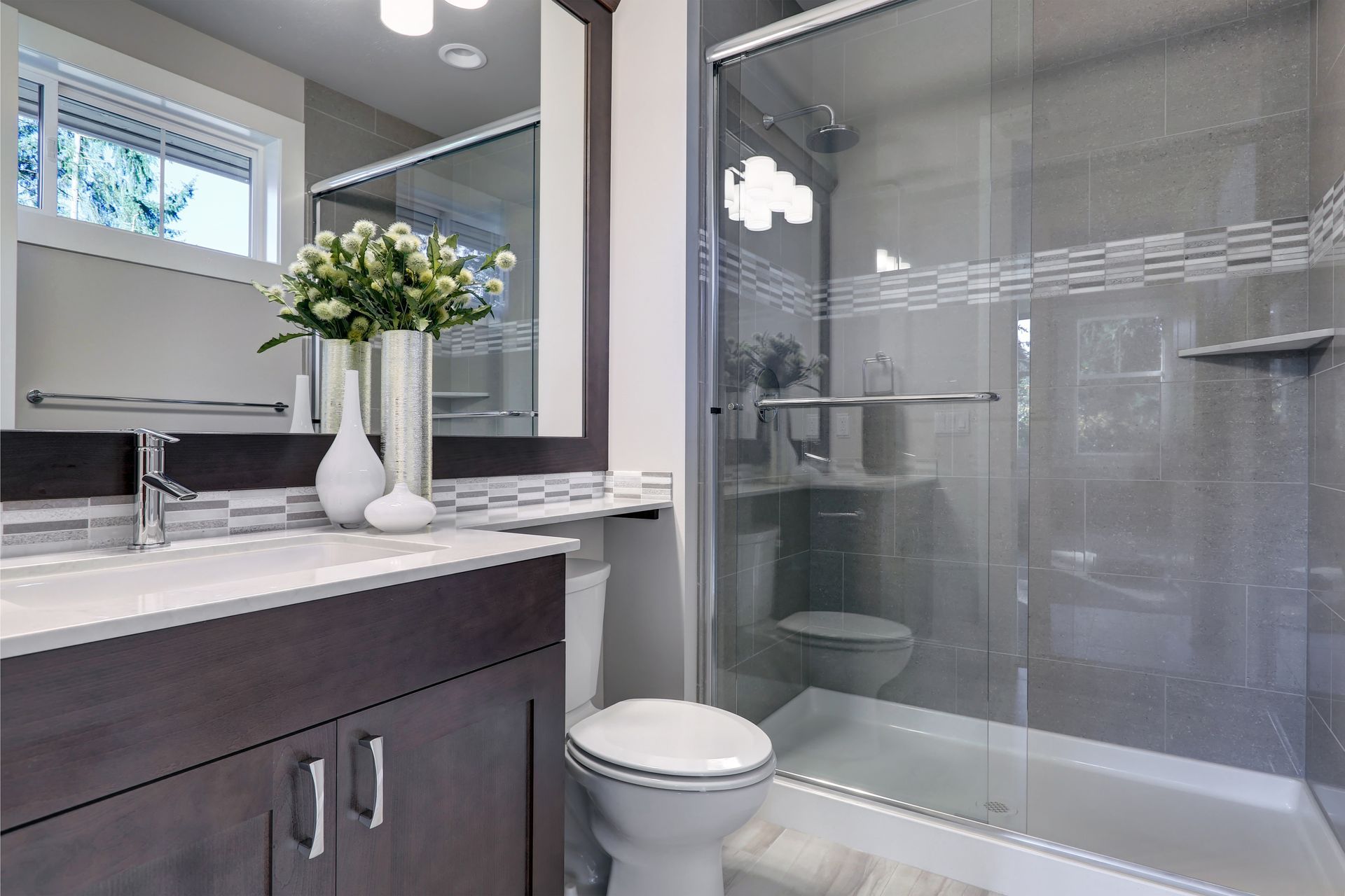 A bathroom with a toilet , sink , mirror and shower stall.