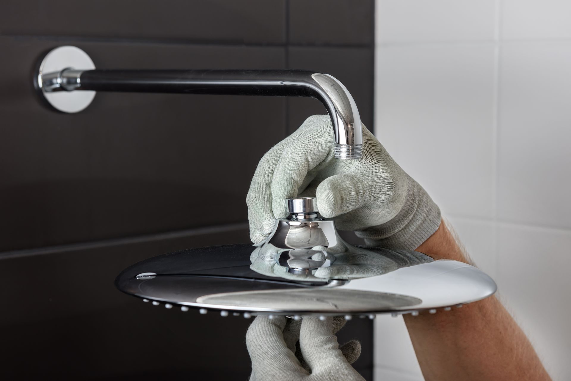 A person is fixing a shower head in a bathroom.