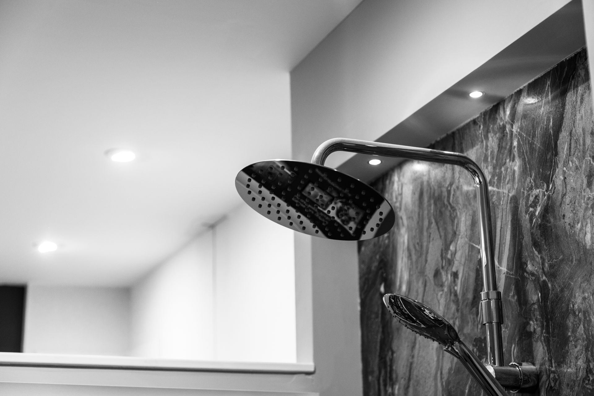 A black and white photo of a shower head in a bathroom.