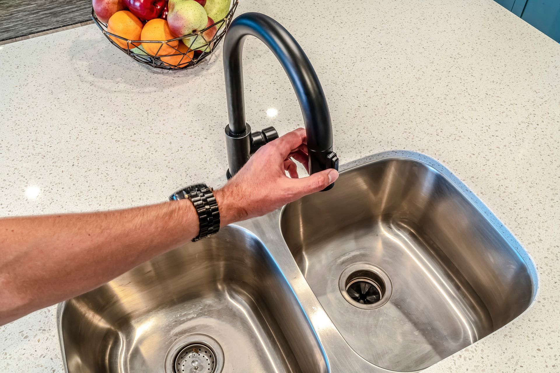 A person is turning on a faucet in a kitchen sink.