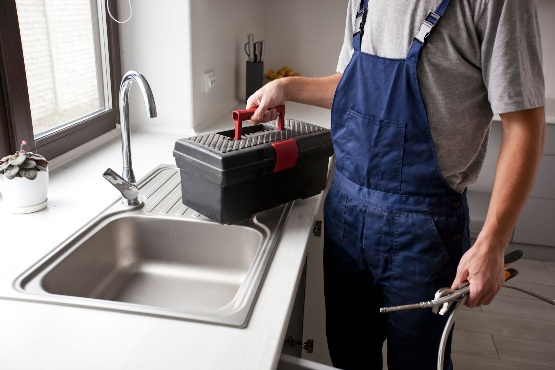 A plumber is fixing a sink in a kitchen.