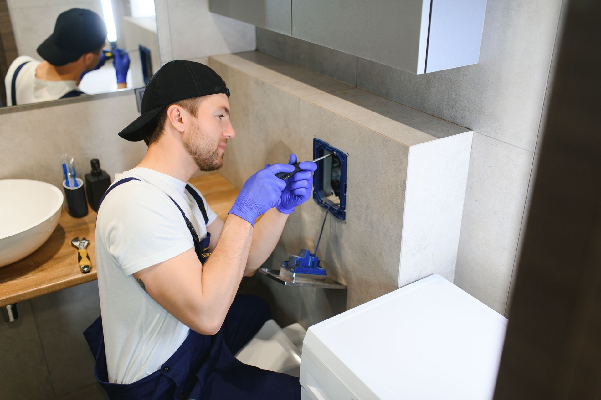 A man is fixing a sink in a bathroom.