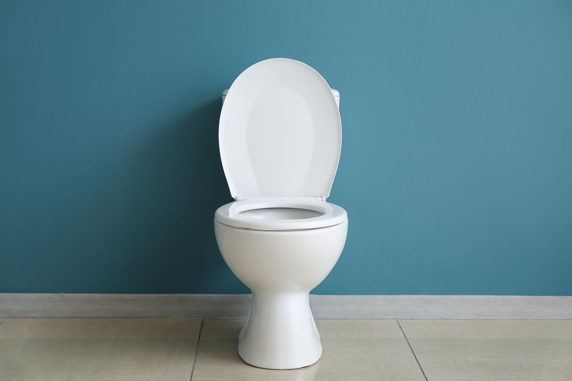 A white toilet is sitting in front of a blue wall.