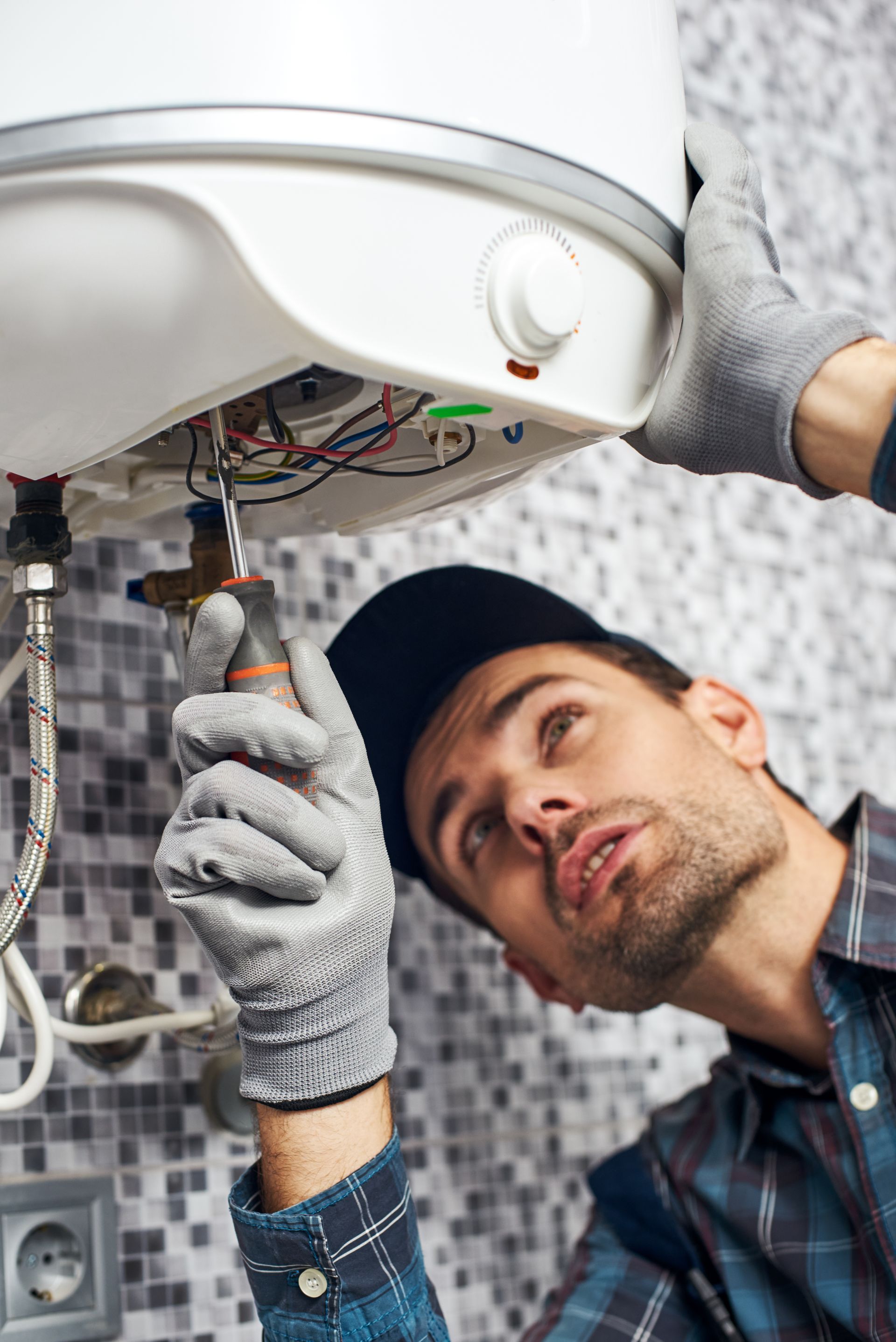 A man is fixing a water heater in a bathroom.