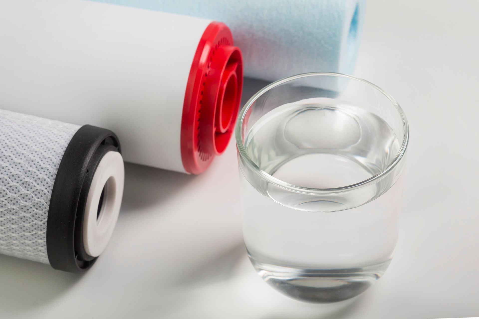 A glass of water next to a filter on a table.