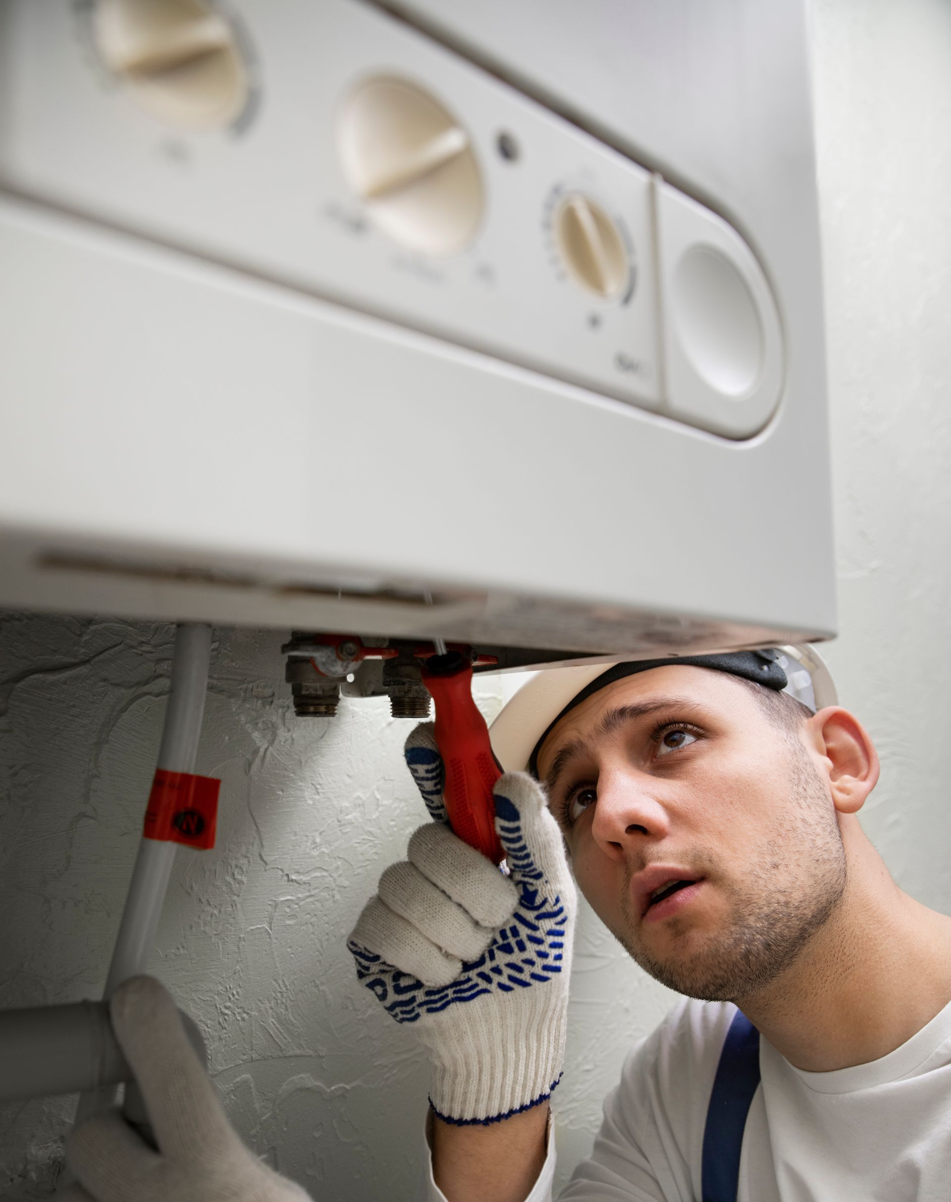 A man is fixing a boiler with a wrench.