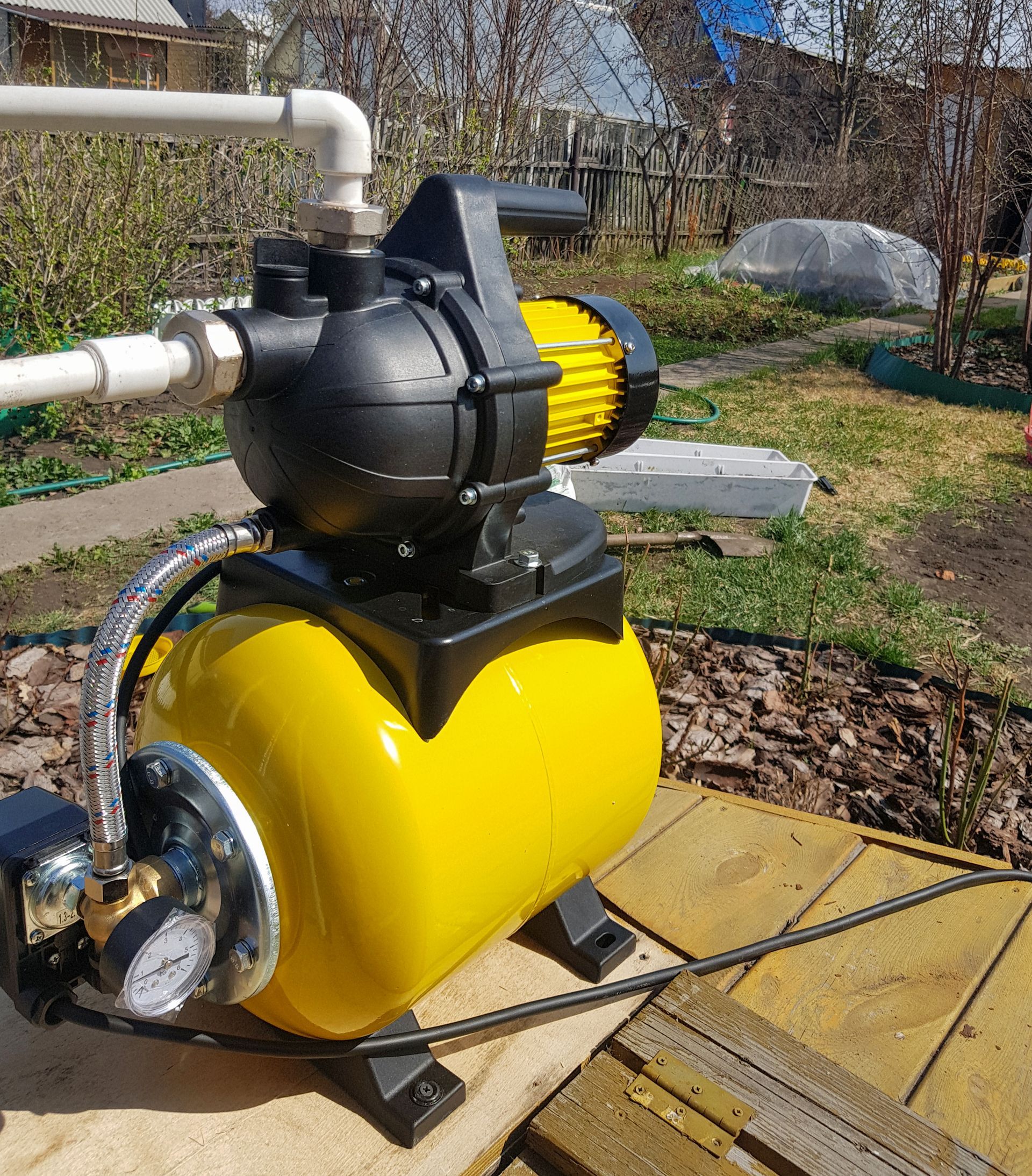 A yellow and black water pump is sitting on a wooden table.