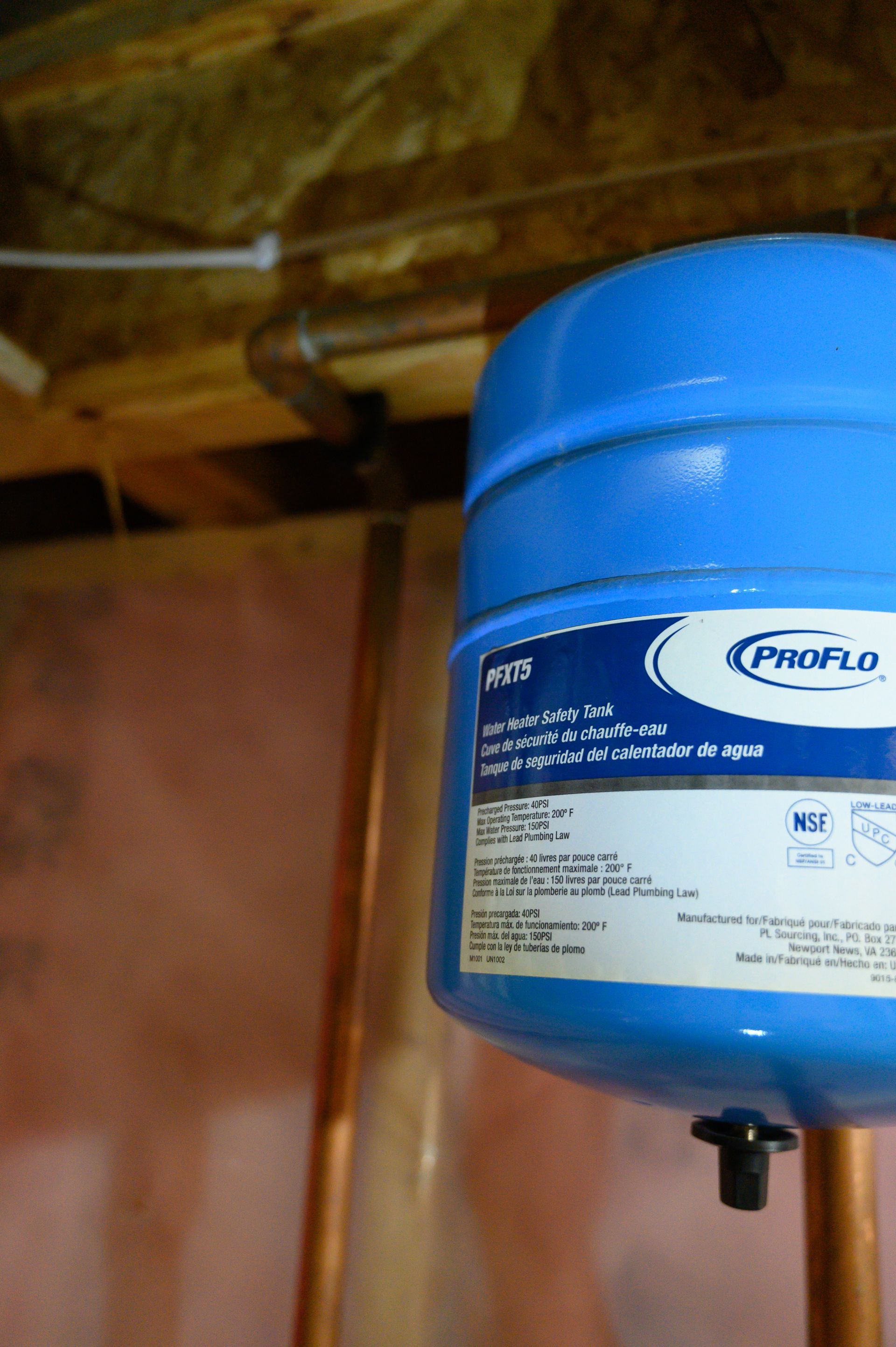 A blue water tank is hanging from a copper pipe.